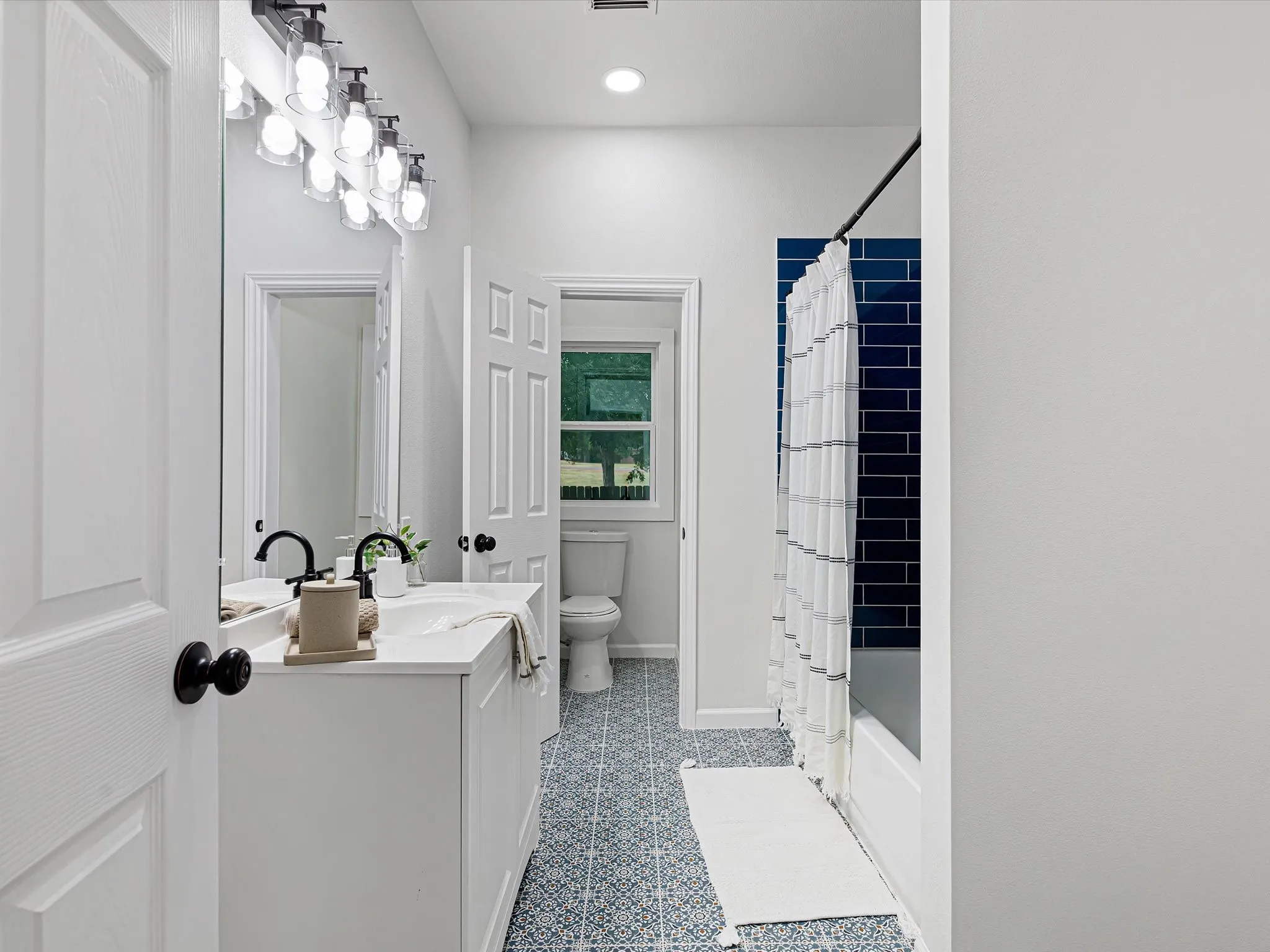 Ensuite primary bathroom is updated featuring cute tile shower, modern tile on the floors, nice lighting, a vanity, etc.