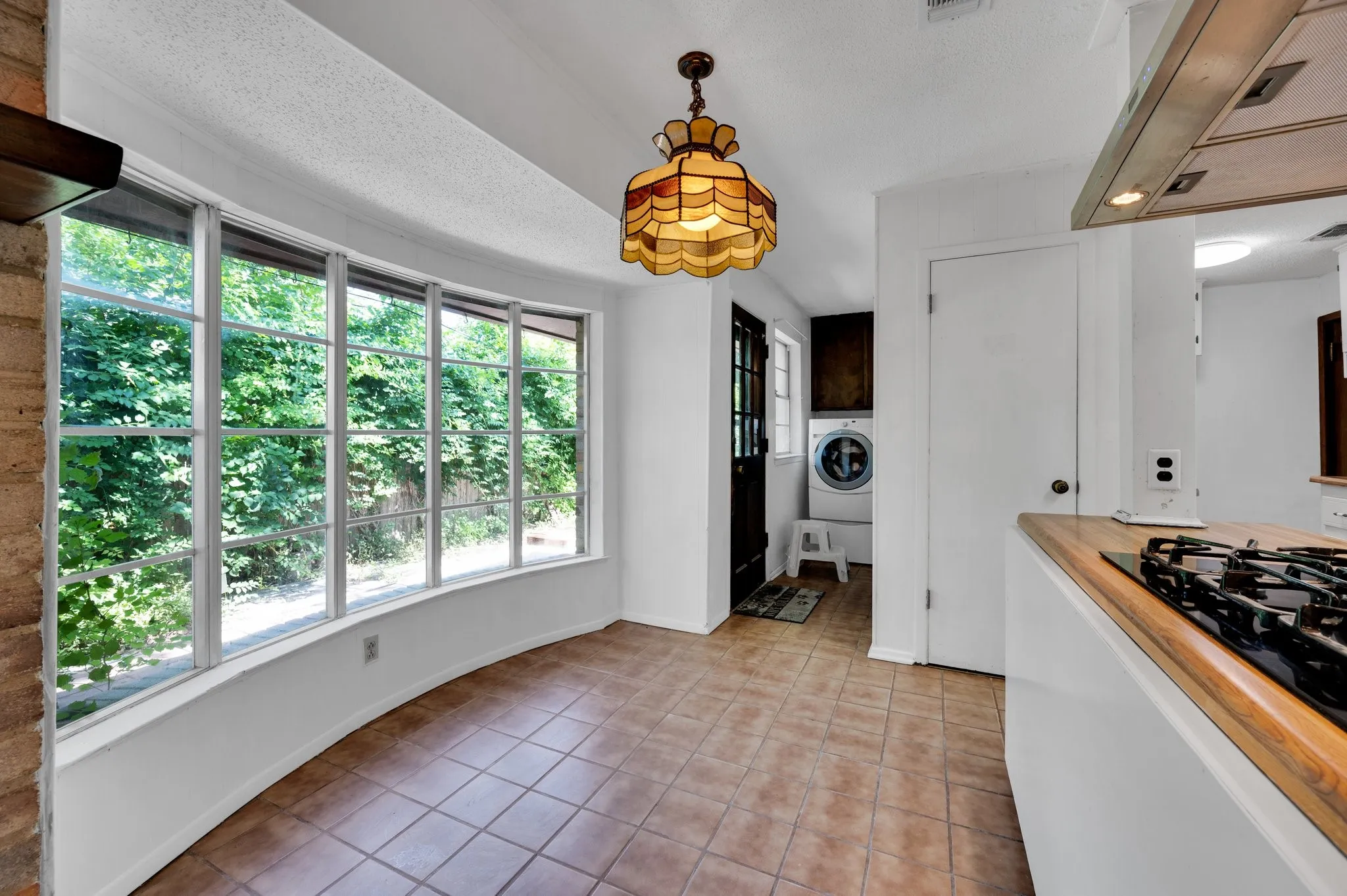 Kitchen with range hood, light tile patterned bay window, flooring, Laundry area, decorative light fixtures, and washer / dryer