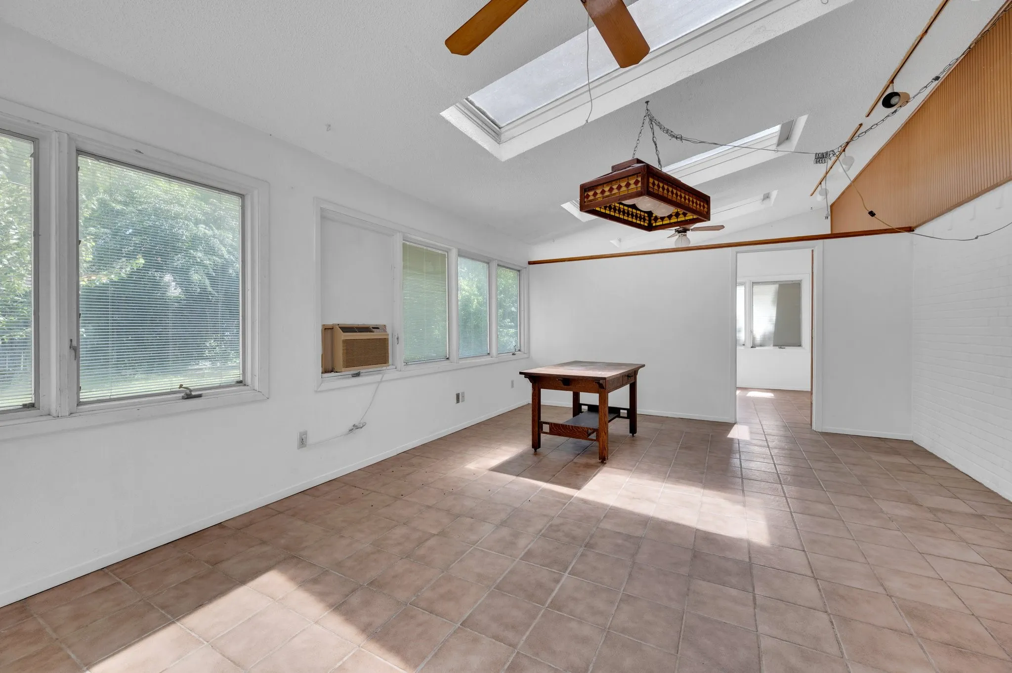 Spare room with a skylight, a ceiling fan, light tile patterned floors, and lofted ceiling