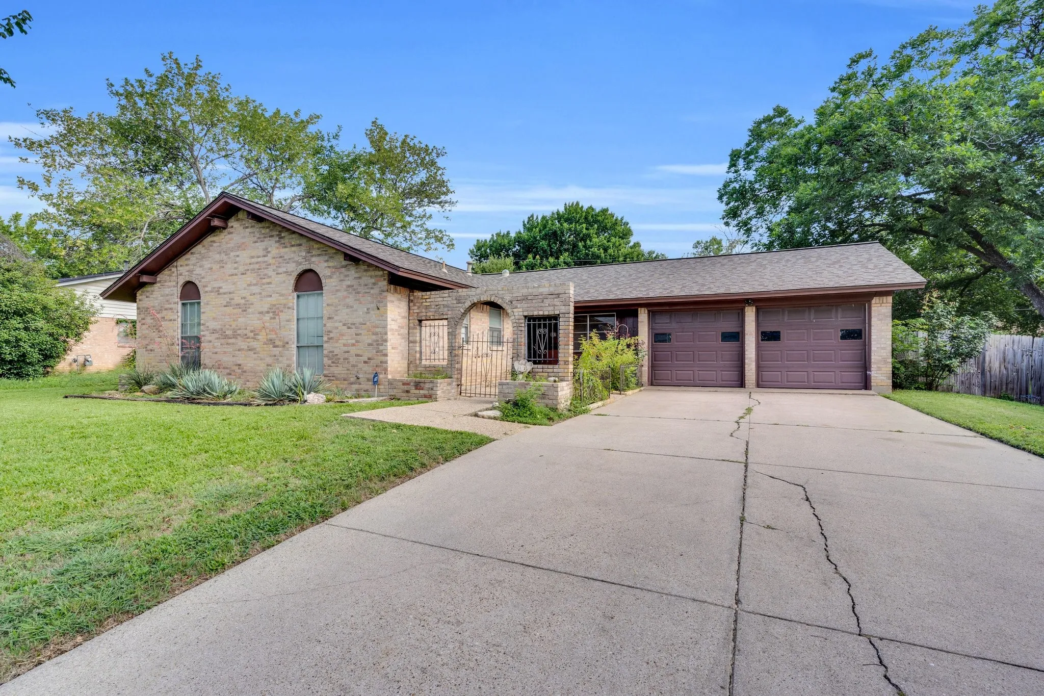 Ranch-style home featuring brick siding, concrete driveway, an attached garage, and roof with shingles