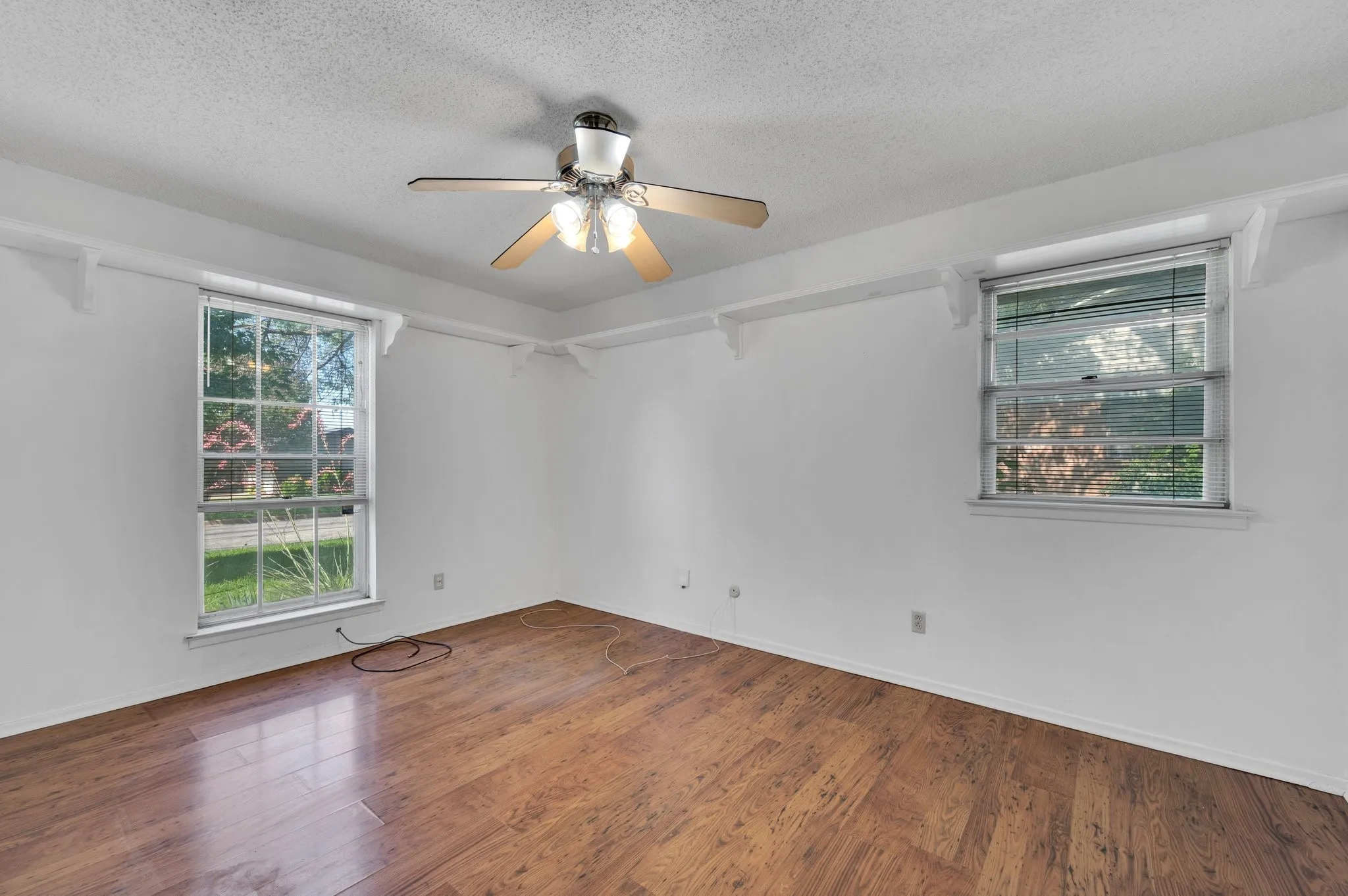 Bedroom 1 room with ceiling fan, a textured ceiling, and wood finished floors