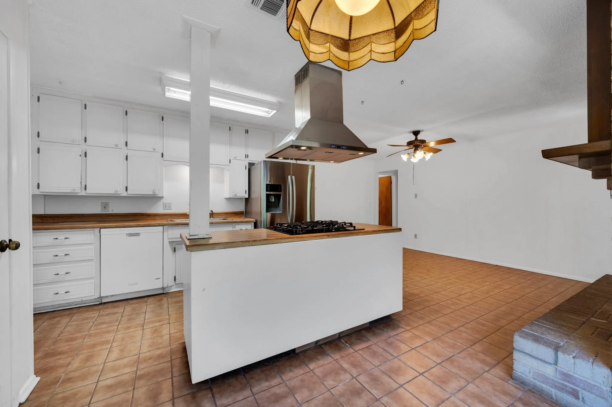Kitchen with island exhaust hood, wooden counters, white cabinets, and white dishwasher