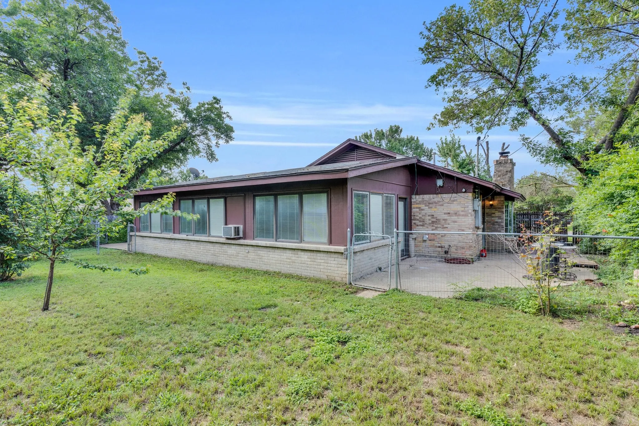Back of house with brick siding, a chimney, and a patio