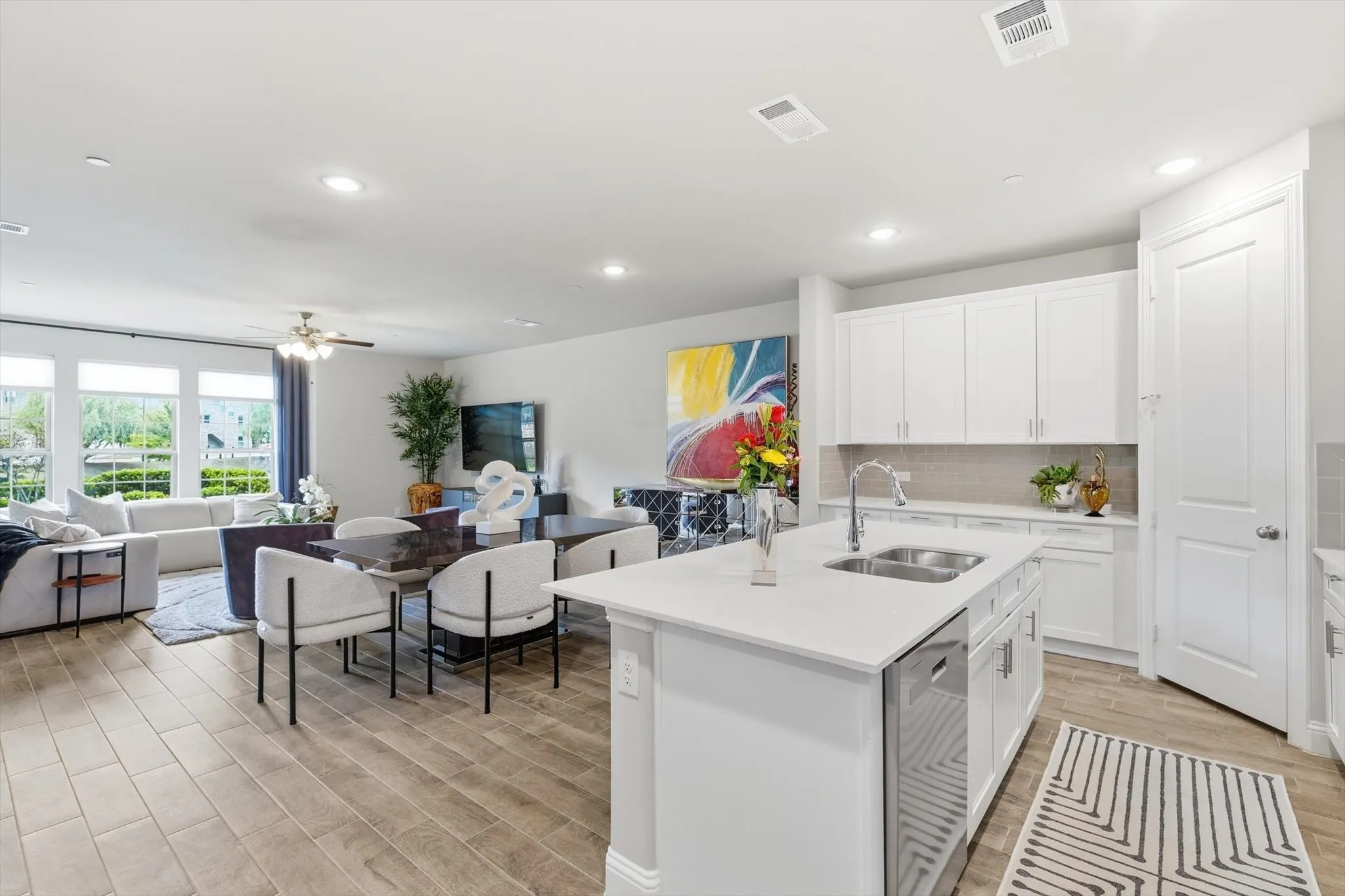 . The Cook’s Kitchen showcases Modern White Shaker-Style Cabinetry, Light-Toned Quartz Countertops, a Spacious Center Island with Breakfast Bar, Soft Gray Subway Tile Backsplash, Recessed Lighting, and Upgraded Wood-Look Tile Flooring for Durability and Warmth. A Full-Height Pantry and Multiple Work Zones enhance Functionality and Flow, seamlessly connecting the Living and Dining Areas for Effortless Entertaining