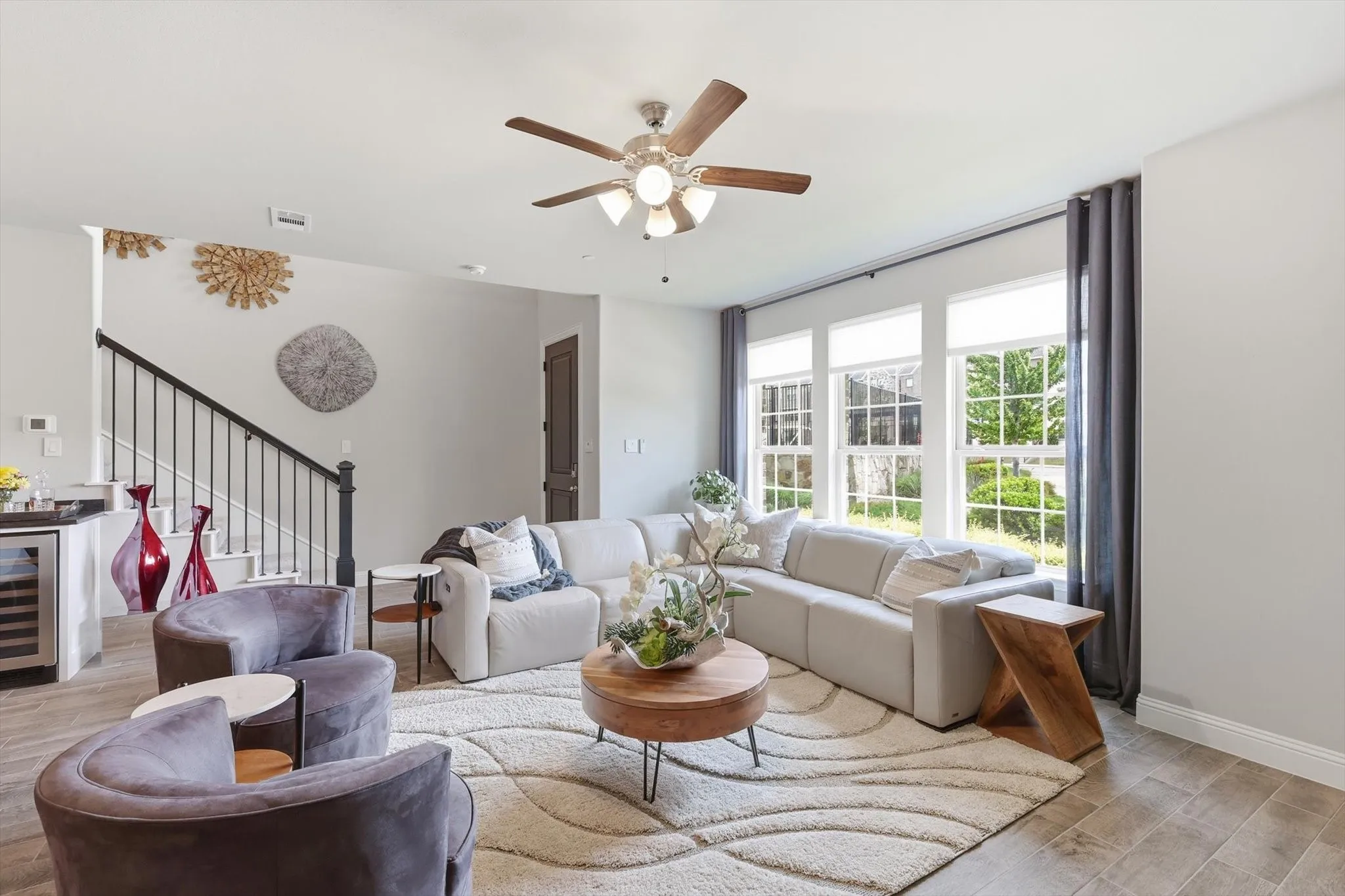 Living Room with a Spacious and Airy Layout, Generous Wall Width, and Large Rectangular Walls ideal for Mounted Installations or Decorative Treatments. A Centered Ceiling Fan, Large Windows, and Power Blinds provide Functional Airflow, Abundant Natural Light, and Privacy, creating a Modern Architectural Feel with High Ceilings, Open Floor Space, and a Neutral Color Palette that supports Flexible Layout and Contemporary Design Styling.