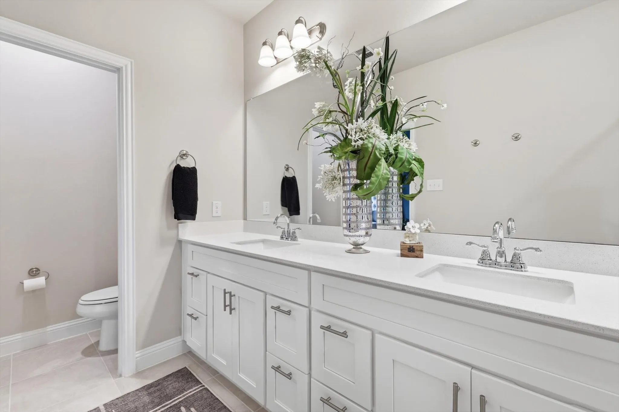 The Luxurious Primary Bathroom features a Raised Mirrored Vanity, Dual Sinks, Quartz Countertops, Designer Lighting, Upgraded Tile Flooring, and a Large Tile Shower.