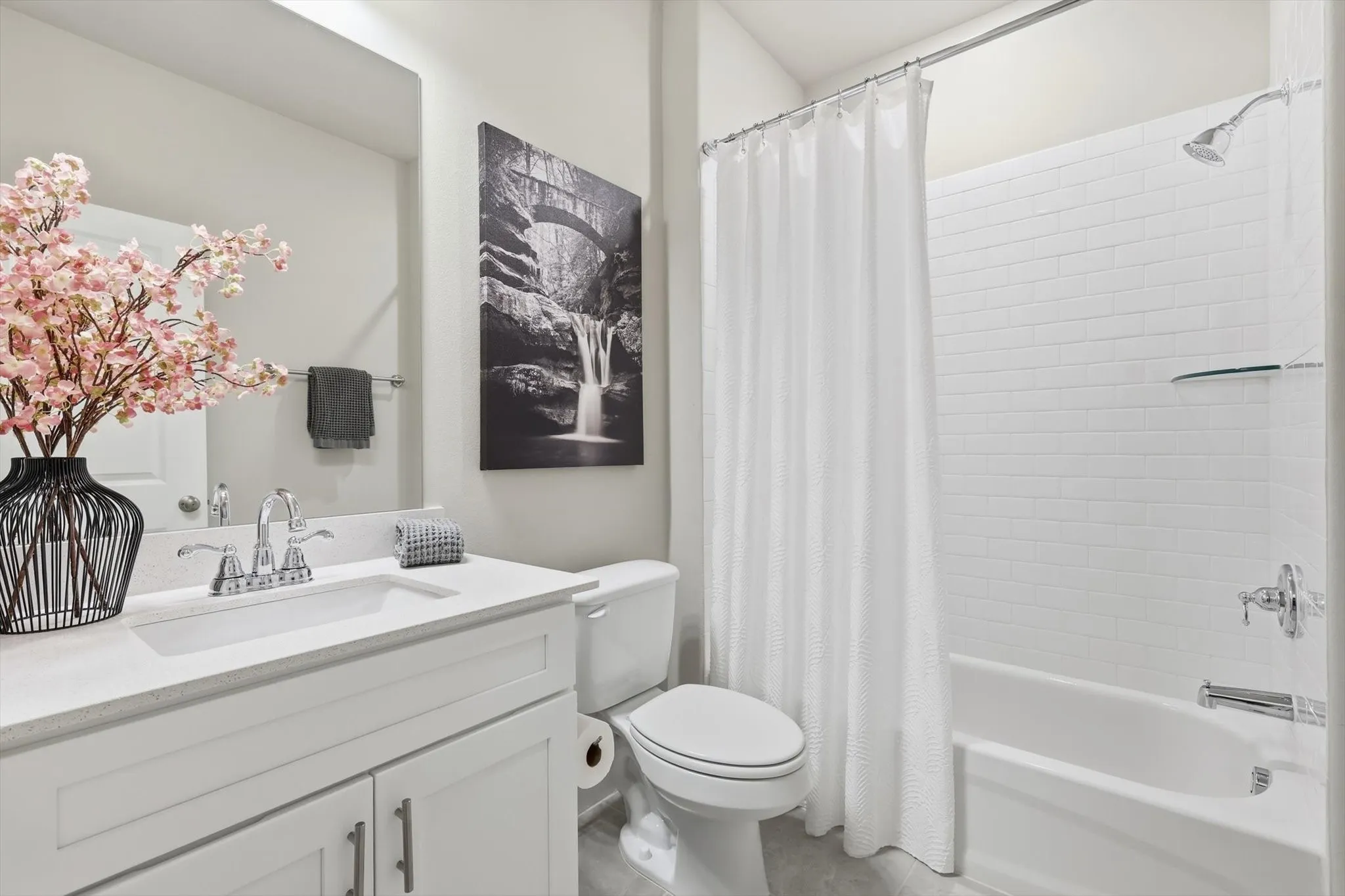 The Main Bath accommodates Both Additional Large Bedrooms and features a Raised Mirrored Vanity with Quartz Counters, Designer Lighting, and Tub with Tile Surround
