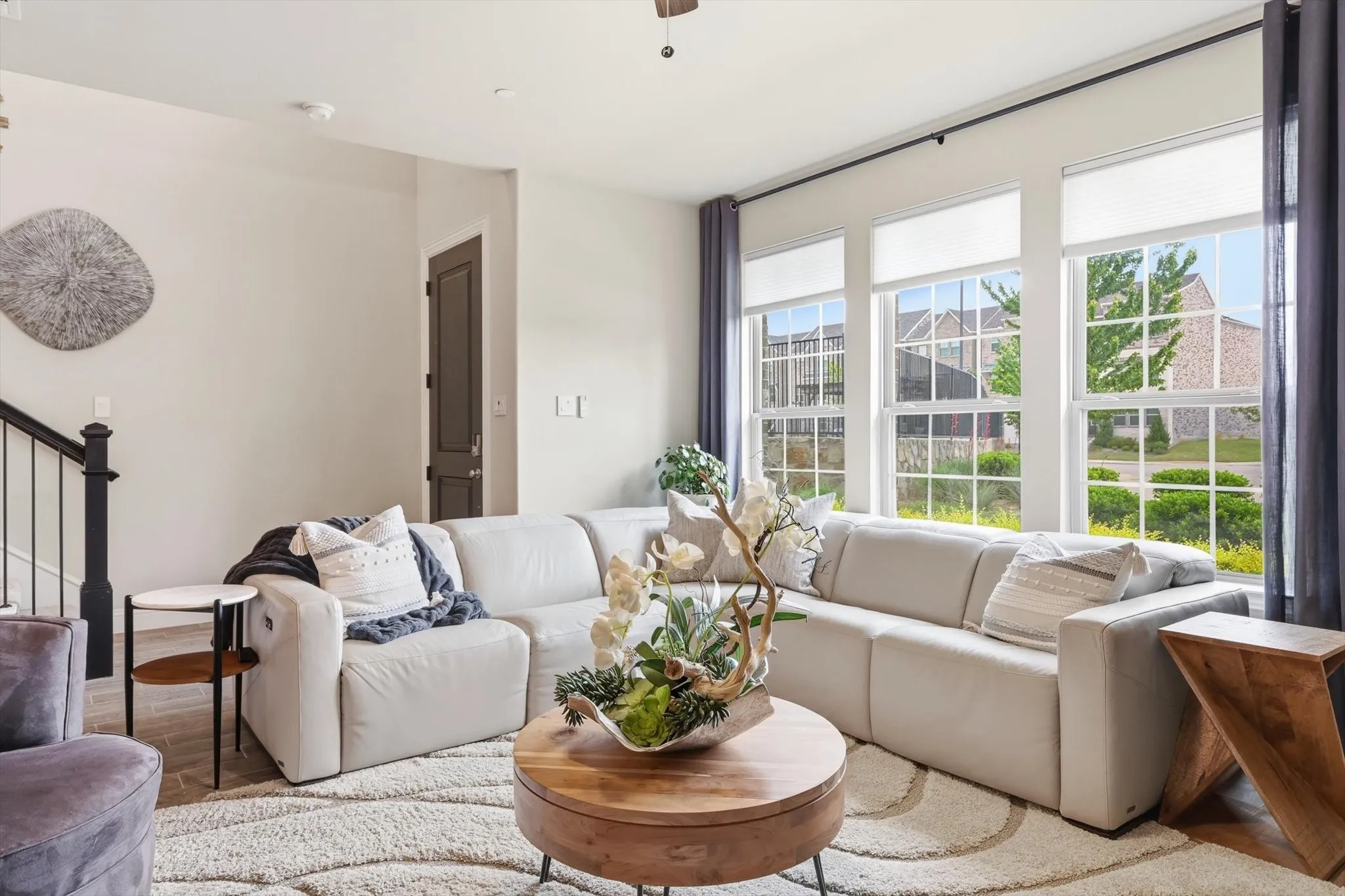 Living Room with a Spacious and Airy Layout, Generous Wall Width, and Large Rectangular Walls ideal for Mounted Installations or Decorative Treatments. A Centered Ceiling Fan, Large Windows, and Power Blinds provide Functional Airflow, Abundant Natural Light, and Privacy, creating a Modern Architectural Feel with High Ceilings, Open Floor Space, and a Neutral Color Palette that supports Flexible Layout and Contemporary Design Styling.