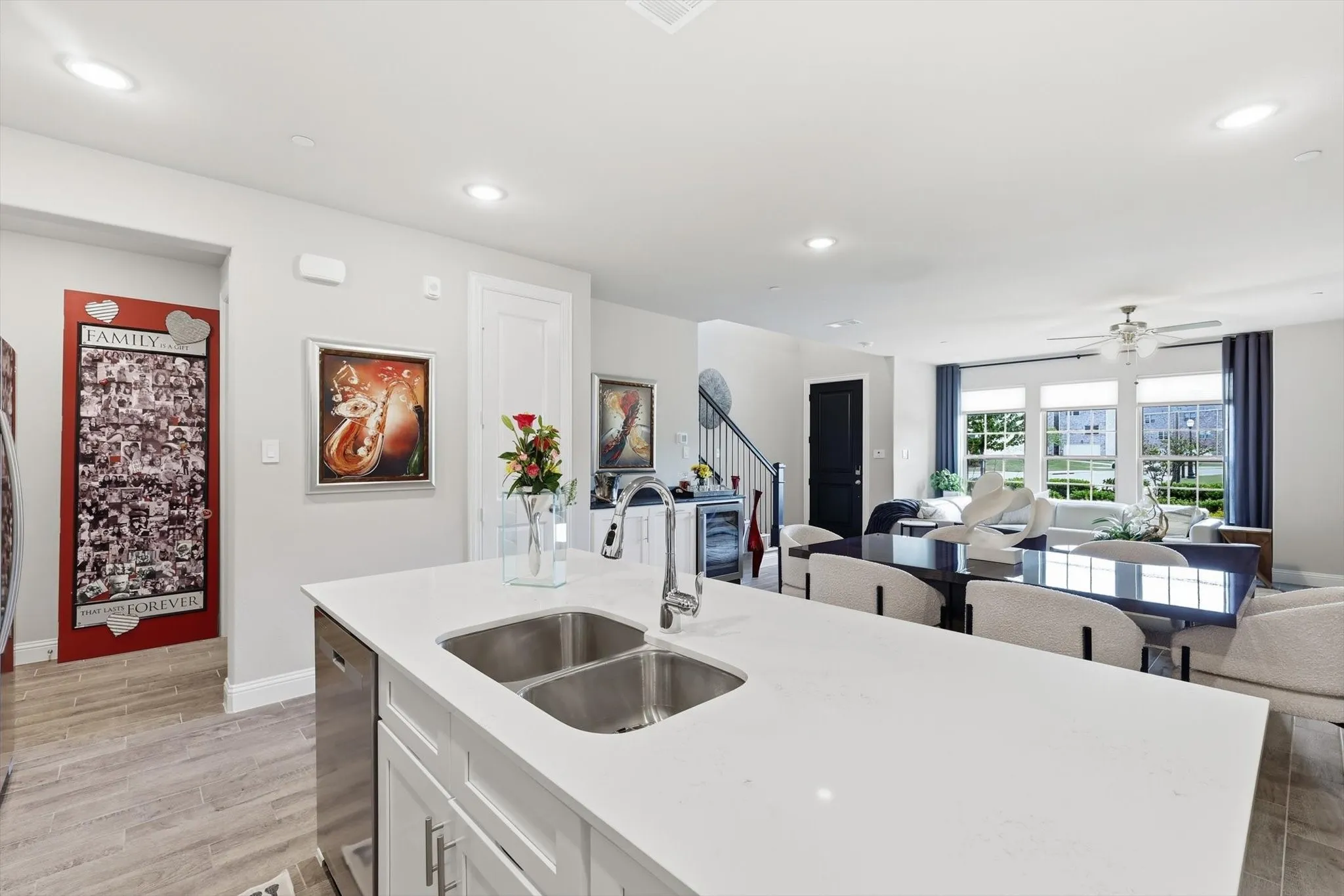 . The Cook’s Kitchen showcases Modern White Shaker-Style Cabinetry, Light-Toned Quartz Countertops, a Spacious Center Island with Breakfast Bar, Soft Gray Subway Tile Backsplash, Recessed Lighting, and Upgraded Wood-Look Tile Flooring for Durability and Warmth. A Full-Height Pantry and Multiple Work Zones enhance Functionality and Flow, seamlessly connecting the Living and Dining Areas for Effortless Entertaining