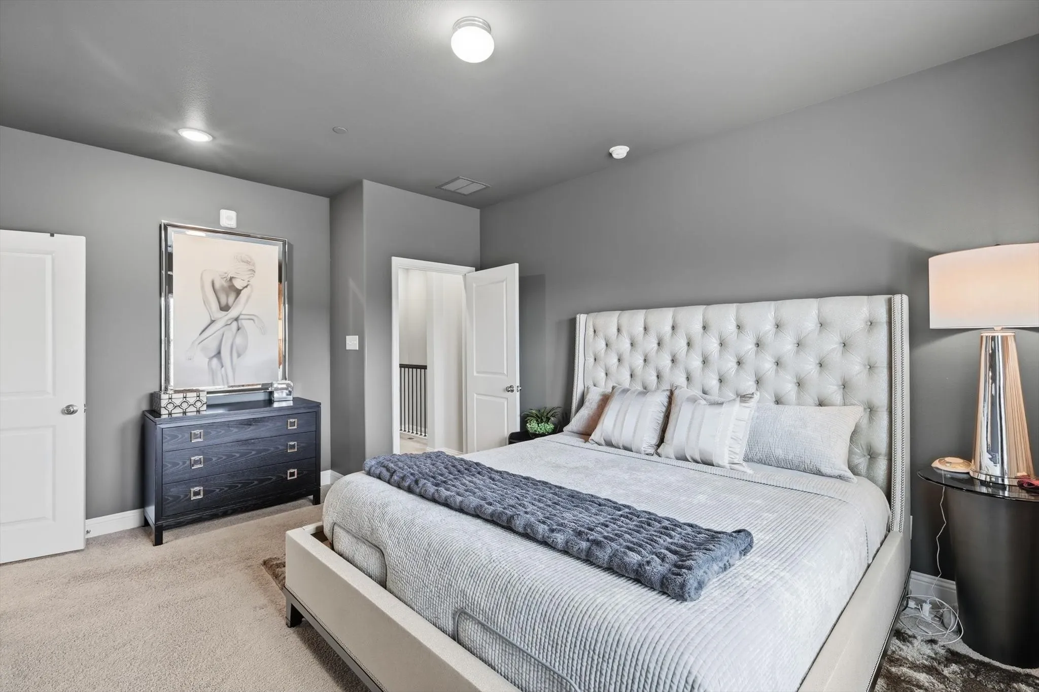 The Primary Bedroom offers a Spacious Layout, Soft Neutral Color Palette, Accent Wall Finish, Large Windows, and Full-Length Drapery, creating a Calm and Private Retreat with Natural Light and Modern Architectural Lines.