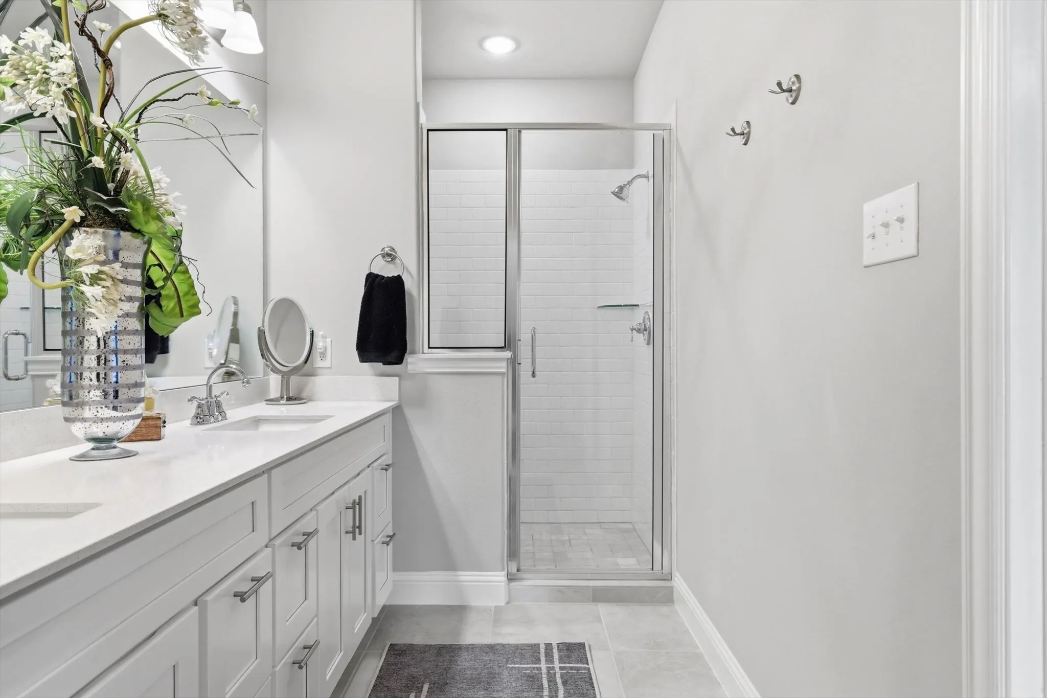The Luxurious Primary Bathroom features a Raised Mirrored Vanity, Dual Sinks, Quartz Countertops, Designer Lighting, Upgraded Tile Flooring, and a Large Tile Shower.