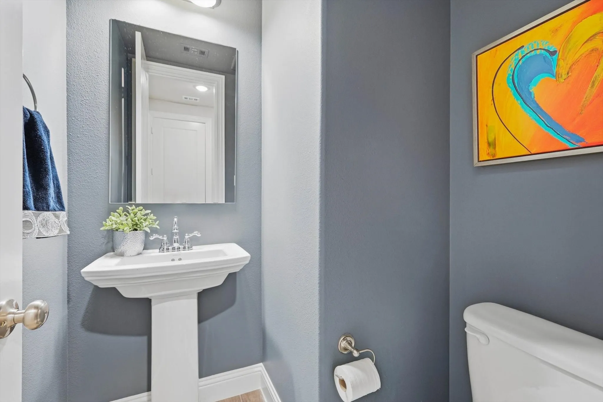 The Powder Room features a Mirrored Pedestal Sink and Designer Lighting.