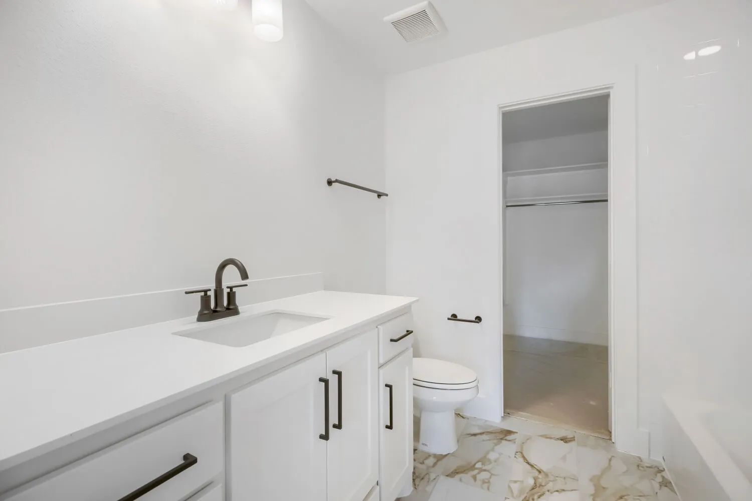 Bathroom featuring a white vanity with integrated sink, dark bronze-finish faucet, and coordinating hardware