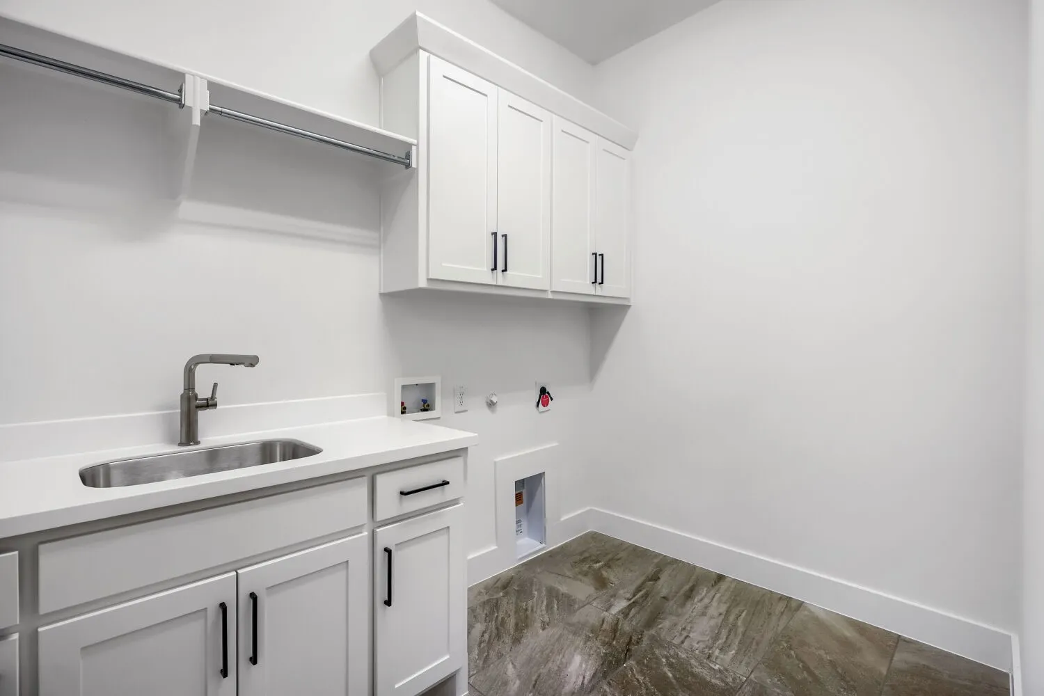 Utility room featuring white cabinetry with black hardware, a stainless steel sink, a modern faucet, and a quartz countertop