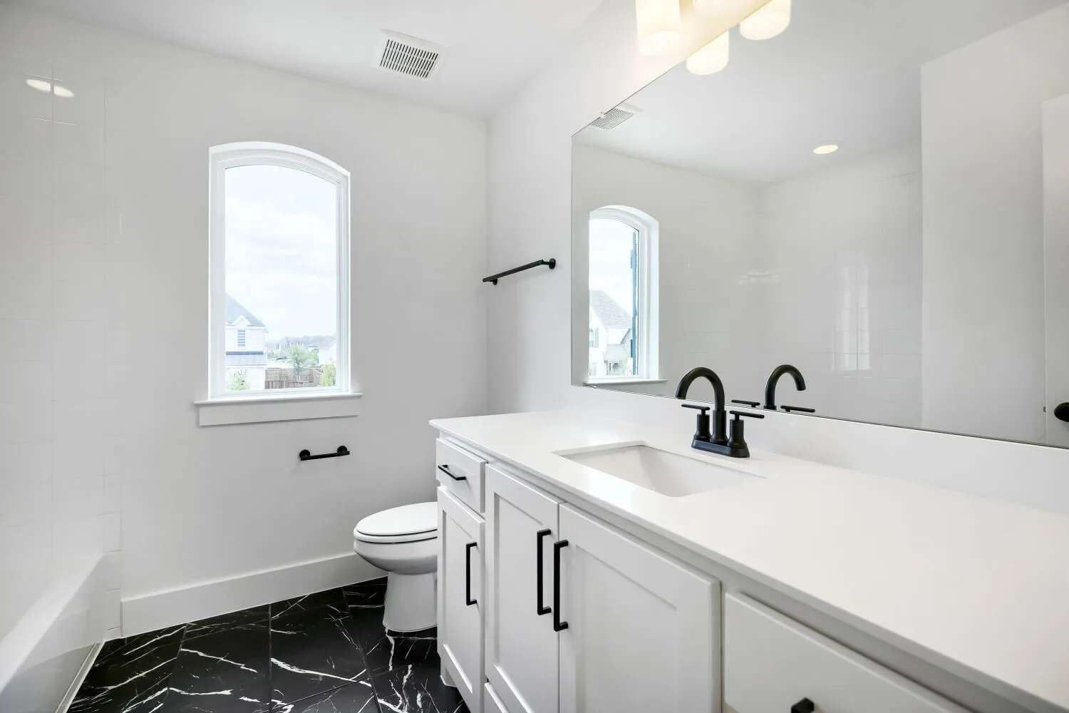 Bathroom featuring a single arched window, white walls, and black-and-white patterned flooring