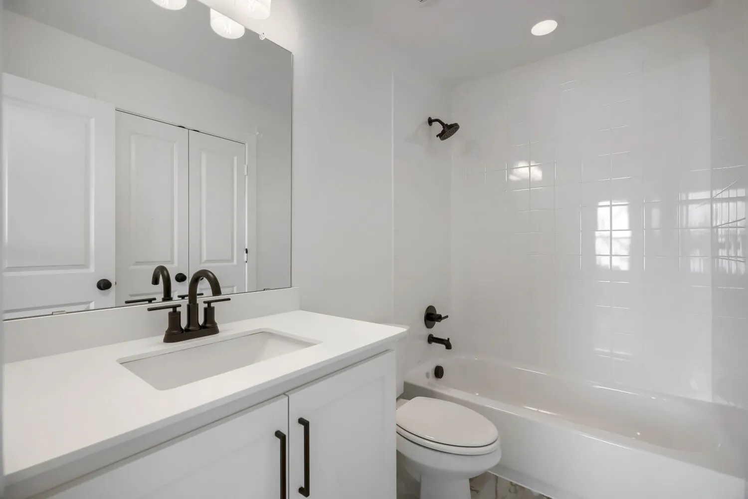 Bathroom featuring a white vanity with an integrated sink, dark bronze hardware, and a framed mirror