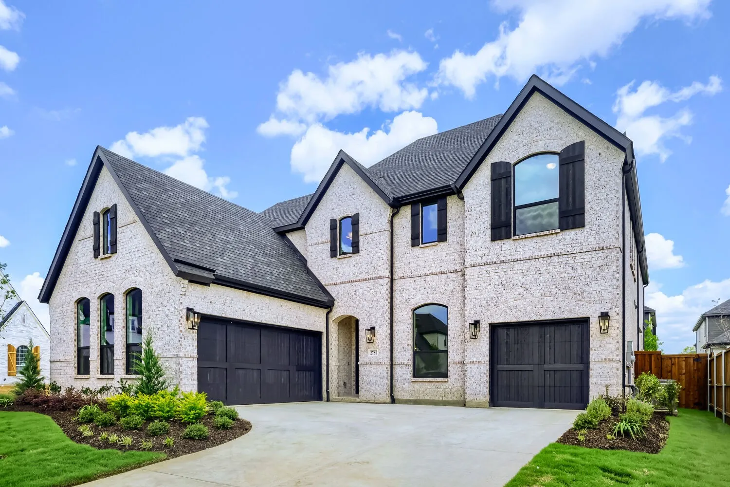 Stately two-story residence featuring a light brick facade and dark-trimmed gables