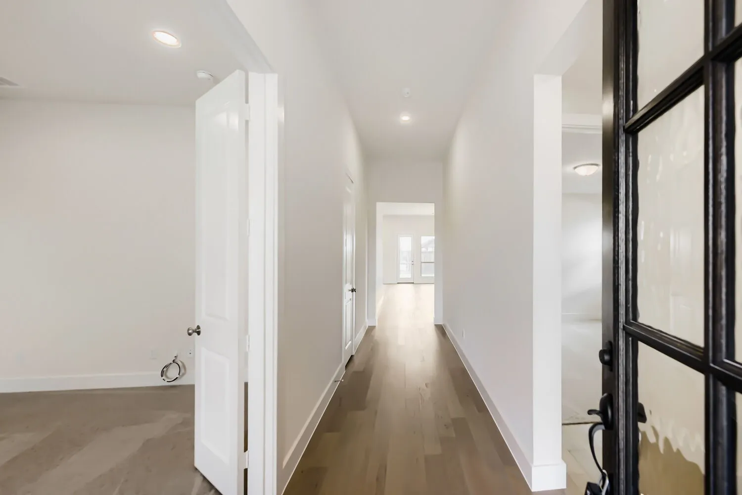 Entryway featuring a dark-frame glass-panel door, wood-finish flooring, recessed lighting, and white baseboards