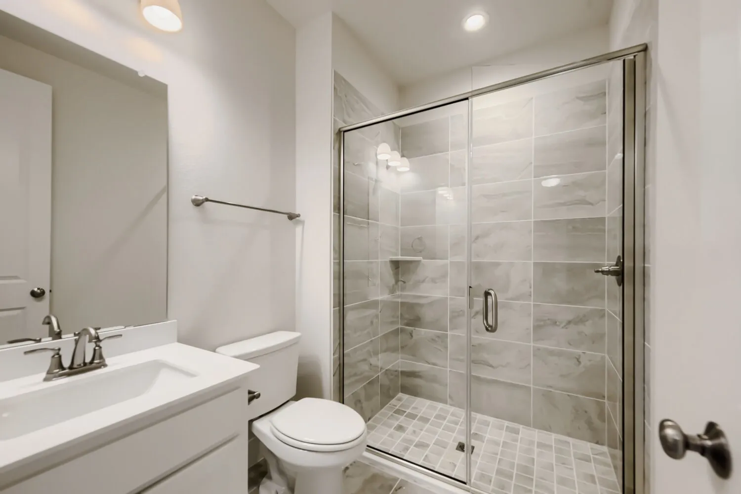 Bathroom featuring a glass-enclosed shower with large format wall tiling and a tiled shower floor