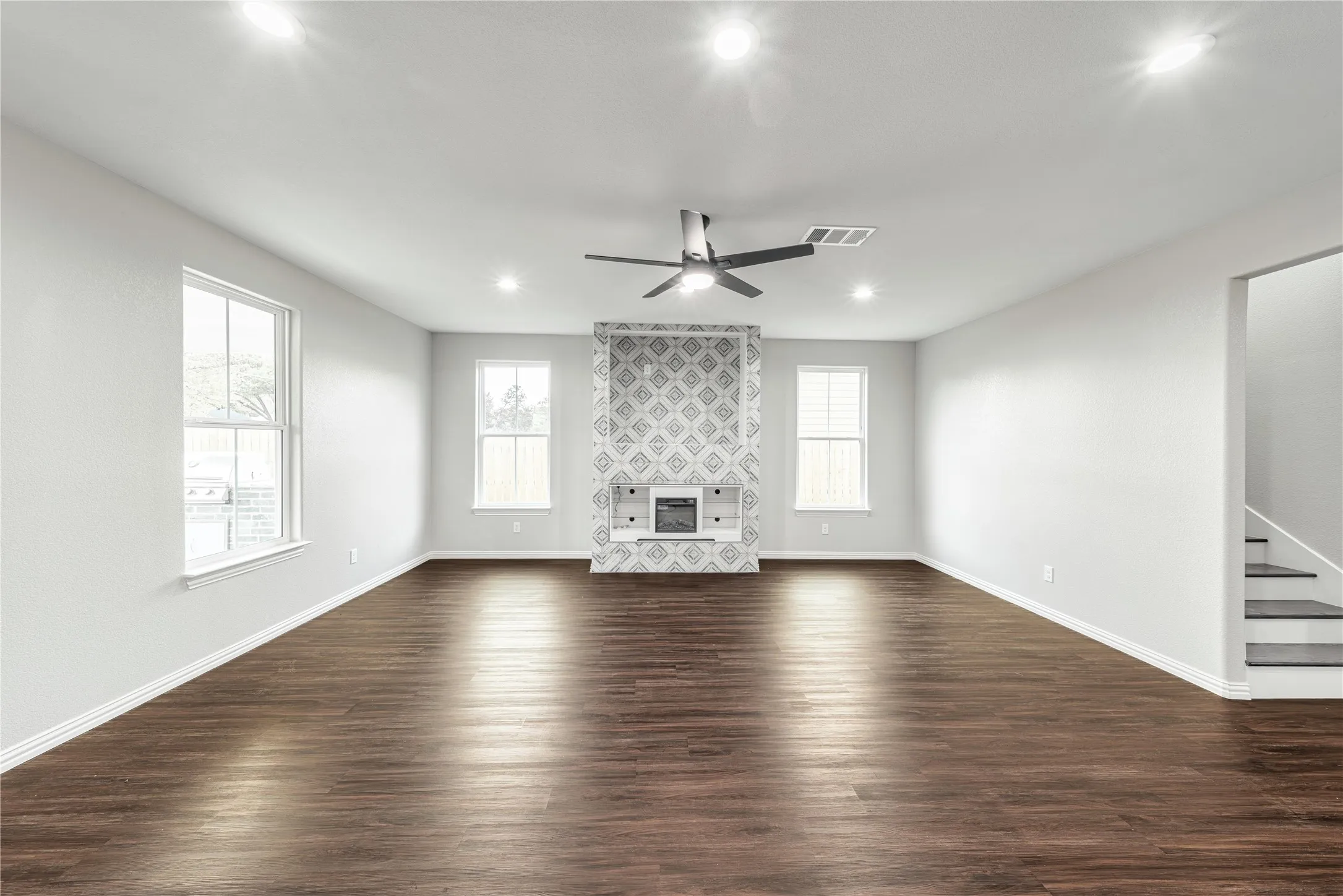 Unfurnished living room featuring dark wood-type finished floors, a ceiling fan, recessed lighting, and a tile fireplace