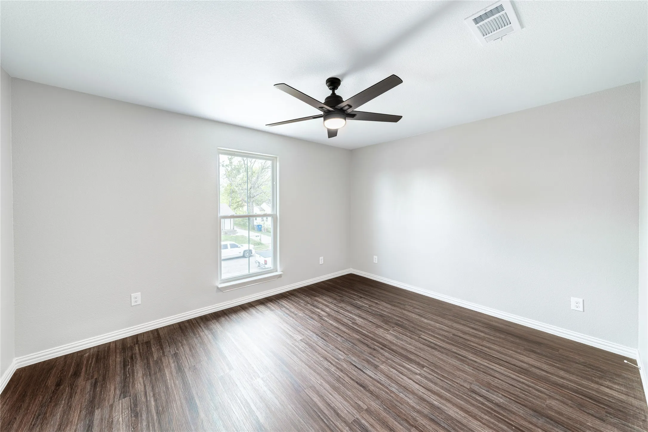 Empty room featuring dark wood-style flooring and ceiling fan