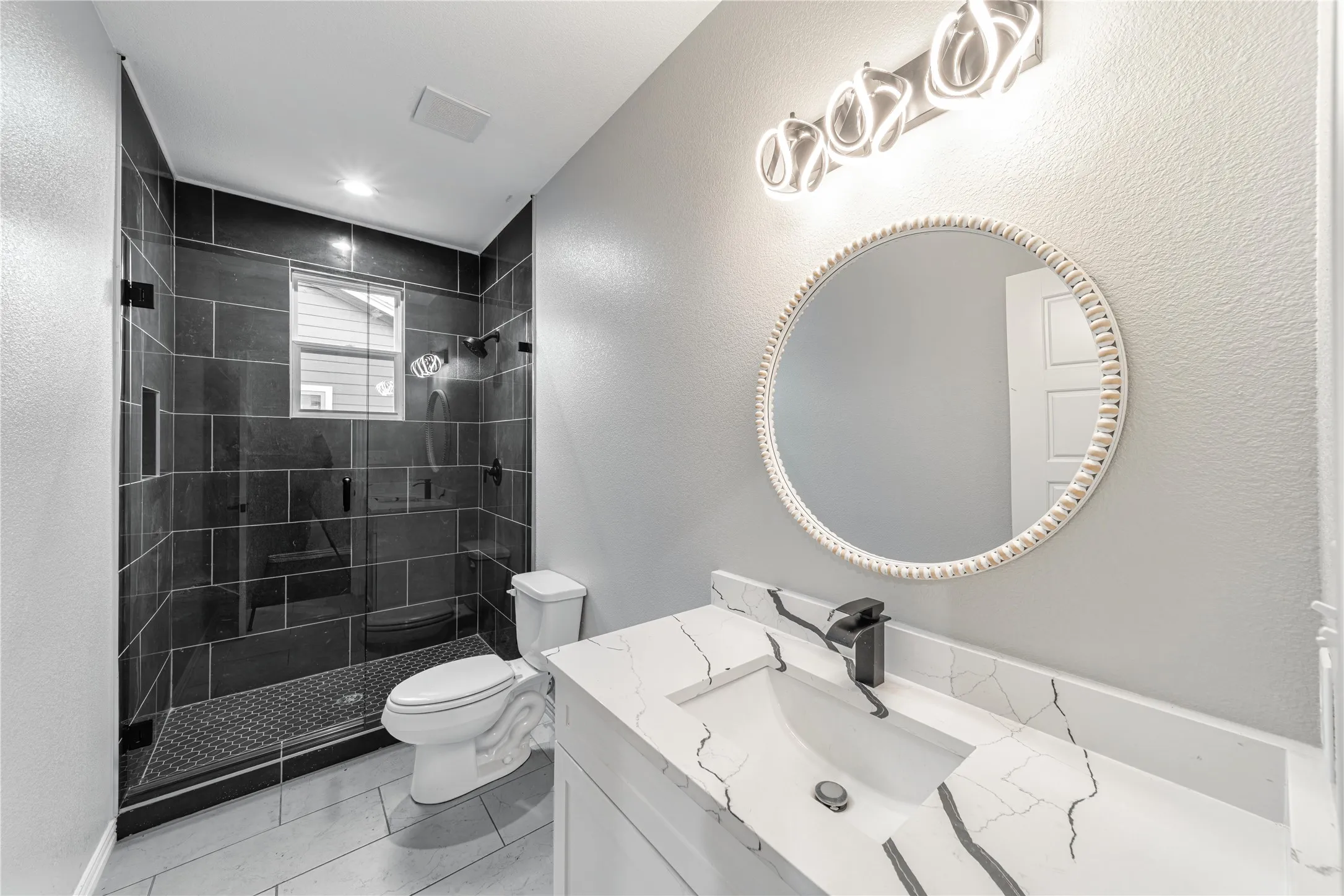 Bathroom with a textured wall, vanity, and a stall shower