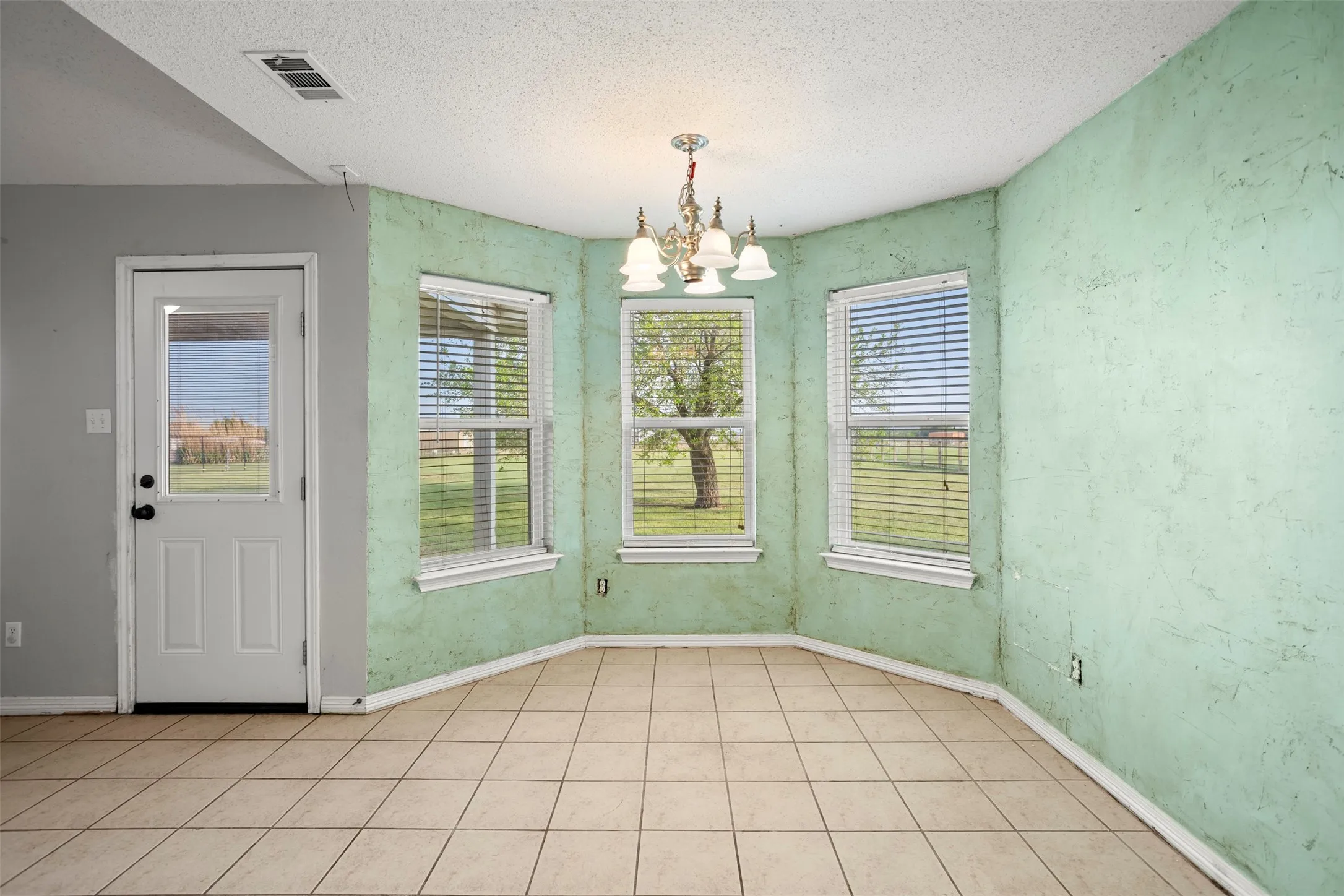 Unfurnished dining area with hanging lights and a textured ceiling