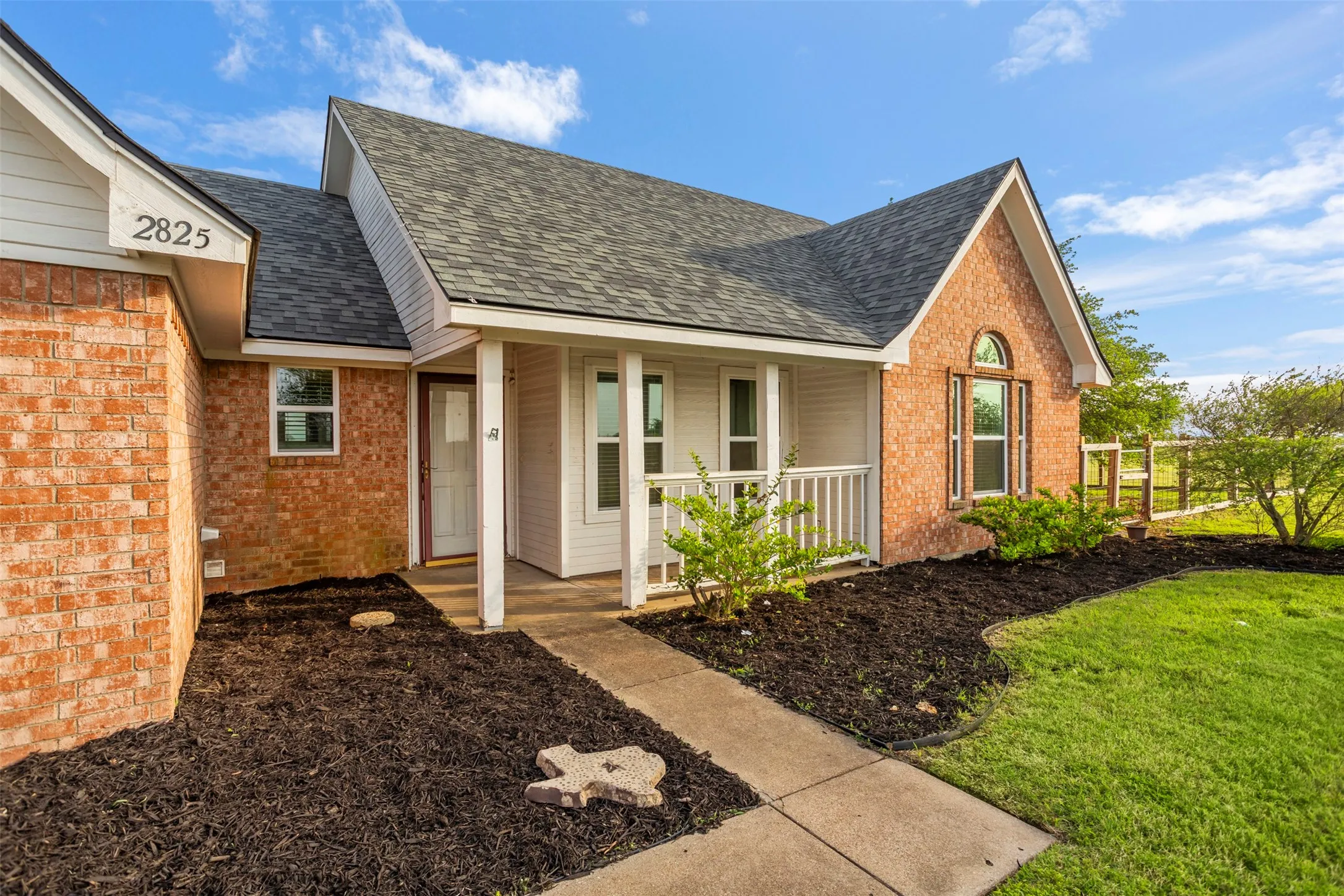 Property entrance featuring brick siding, a porch, and roof with shingles