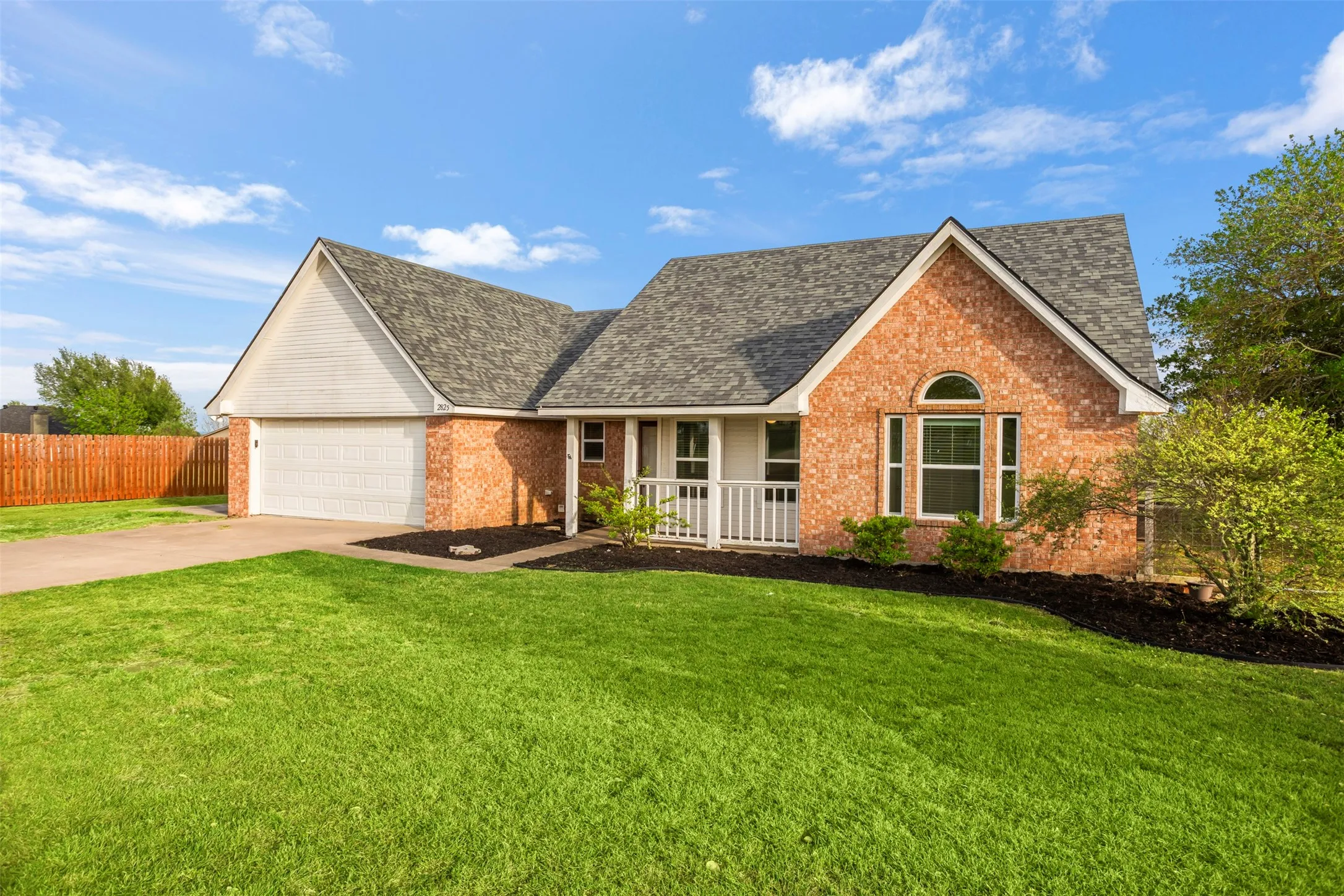 View of front of home with brick siding, a garage, concrete driveway, and a shingled roof