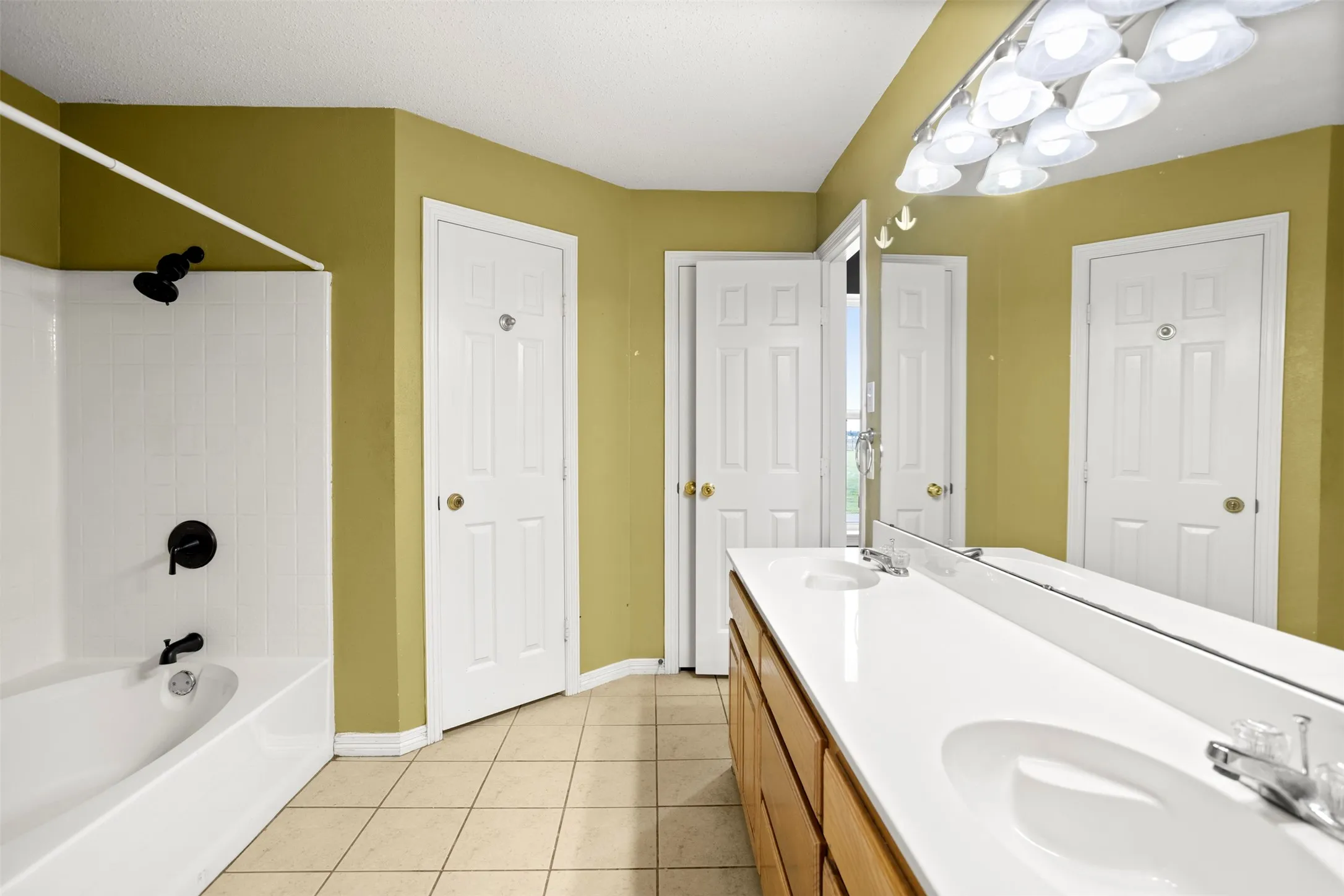 Full bathroom with double vanity, light tile patterned flooring, and  shower combination