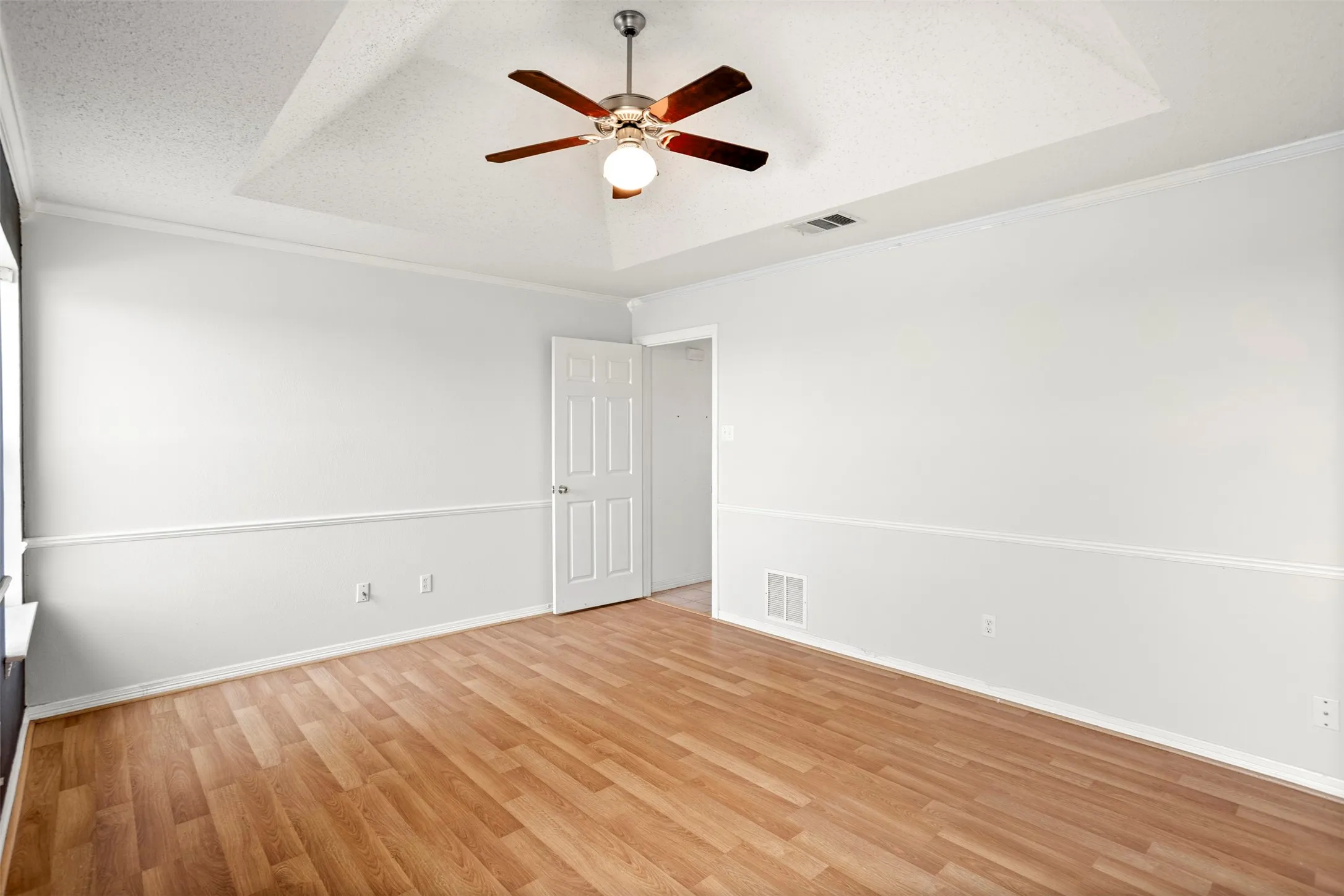 Empty room featuring crown molding, a textured ceiling, a ceiling fan, and light wood-type flooring