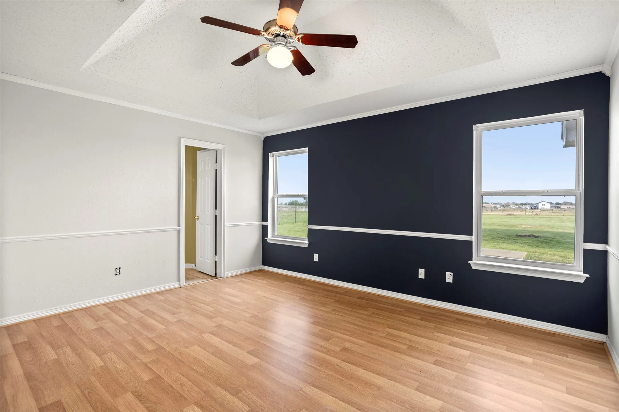 Spare room with ornamental molding, ceiling fan, a textured ceiling, and light wood finished floors