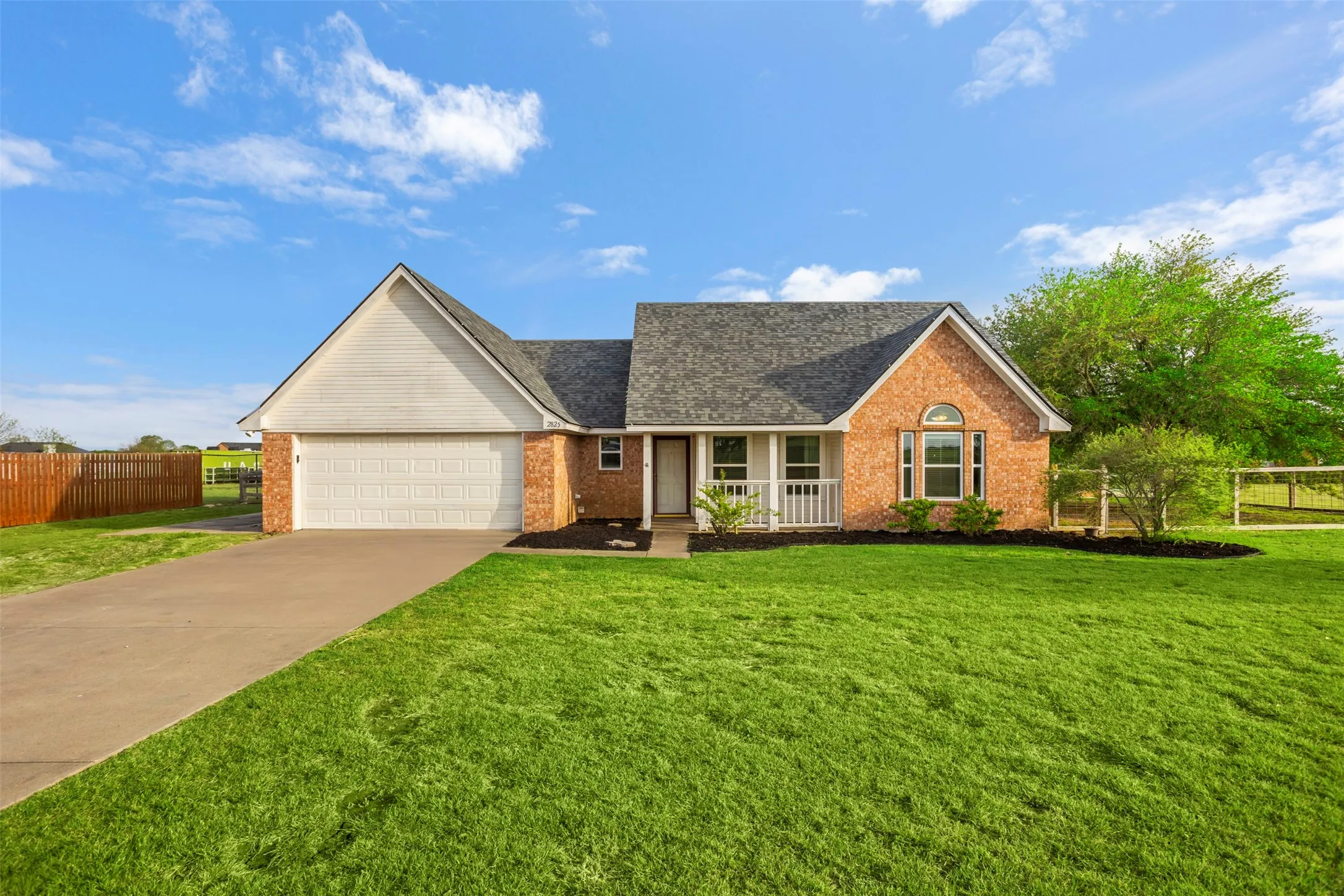 View of front facade featuring brick siding, a garage, driveway, and covered porch