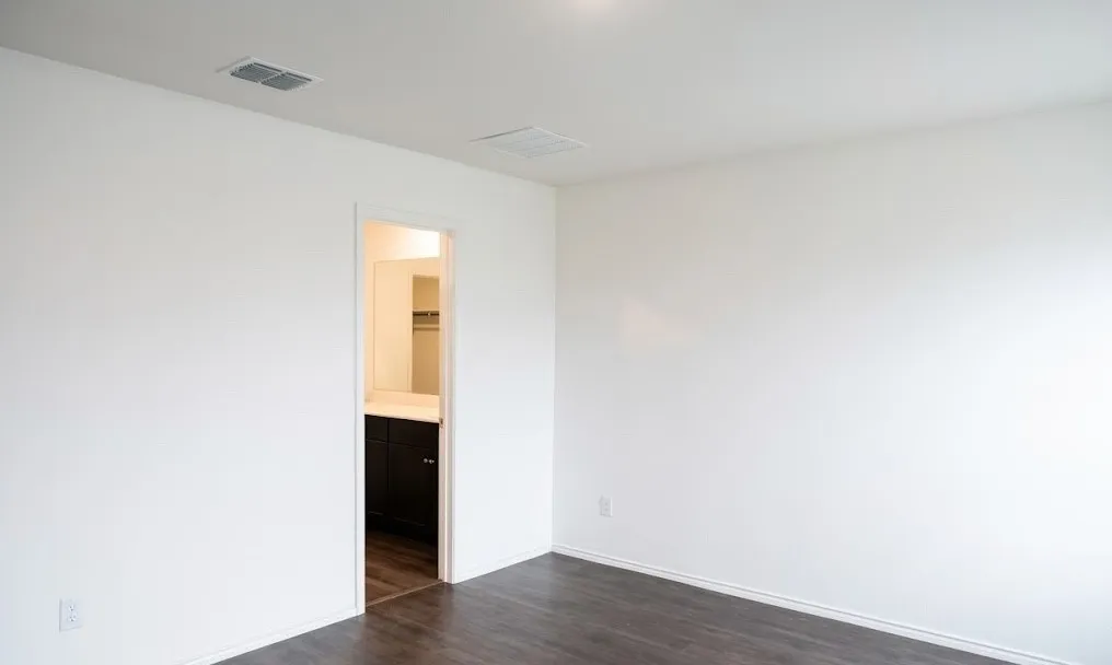 Unfurnished bedroom with dark wood-style floors and connected bathroom