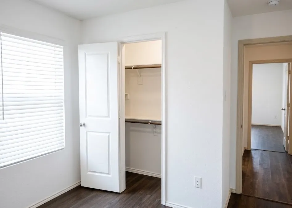 Unfurnished bedroom featuring a spacious closet and dark wood-style floors