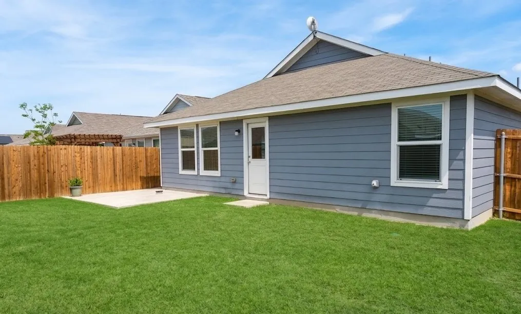 Back of house featuring a fenced backyard, a patio, and roof with shingles