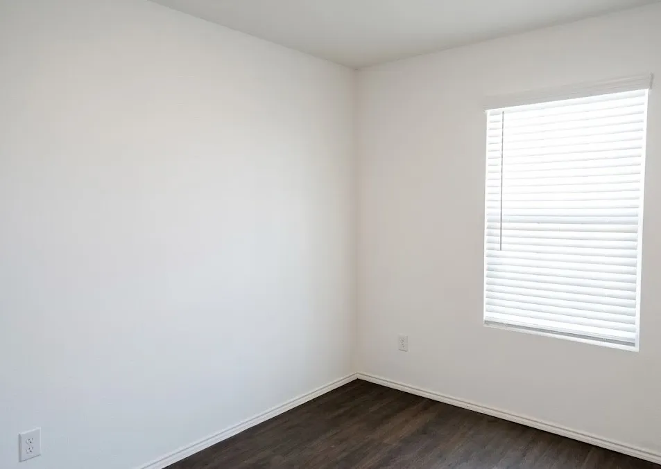 Empty room with dark wood-type flooring and baseboards