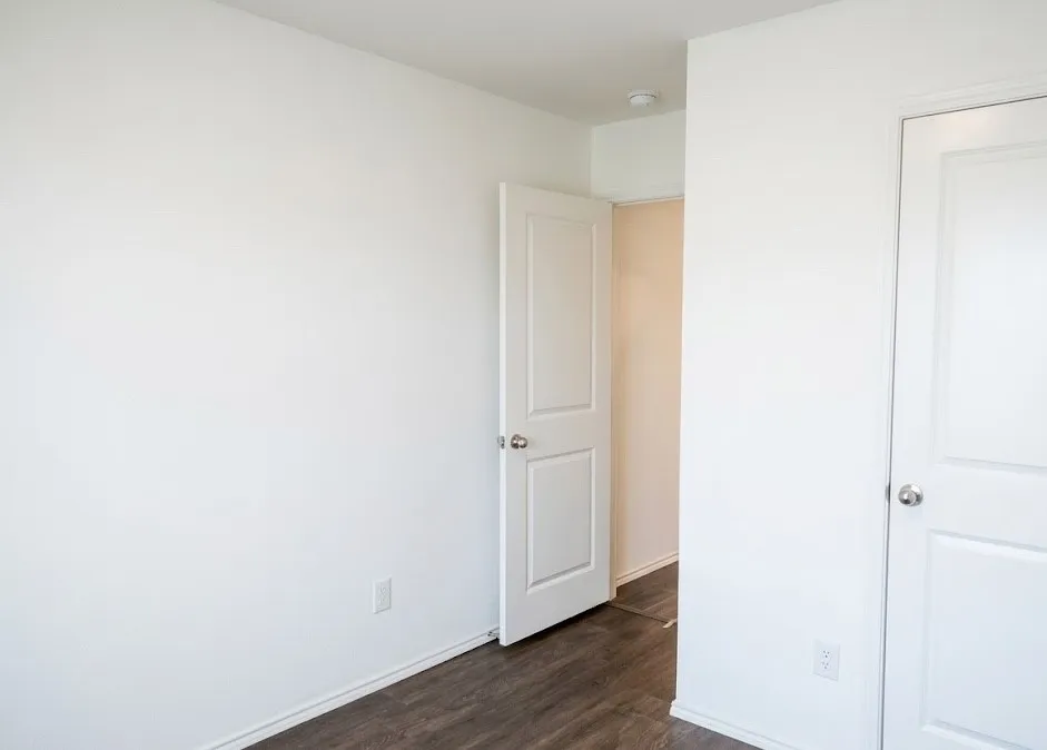 Unfurnished bedroom featuring dark wood finished floors and baseboards