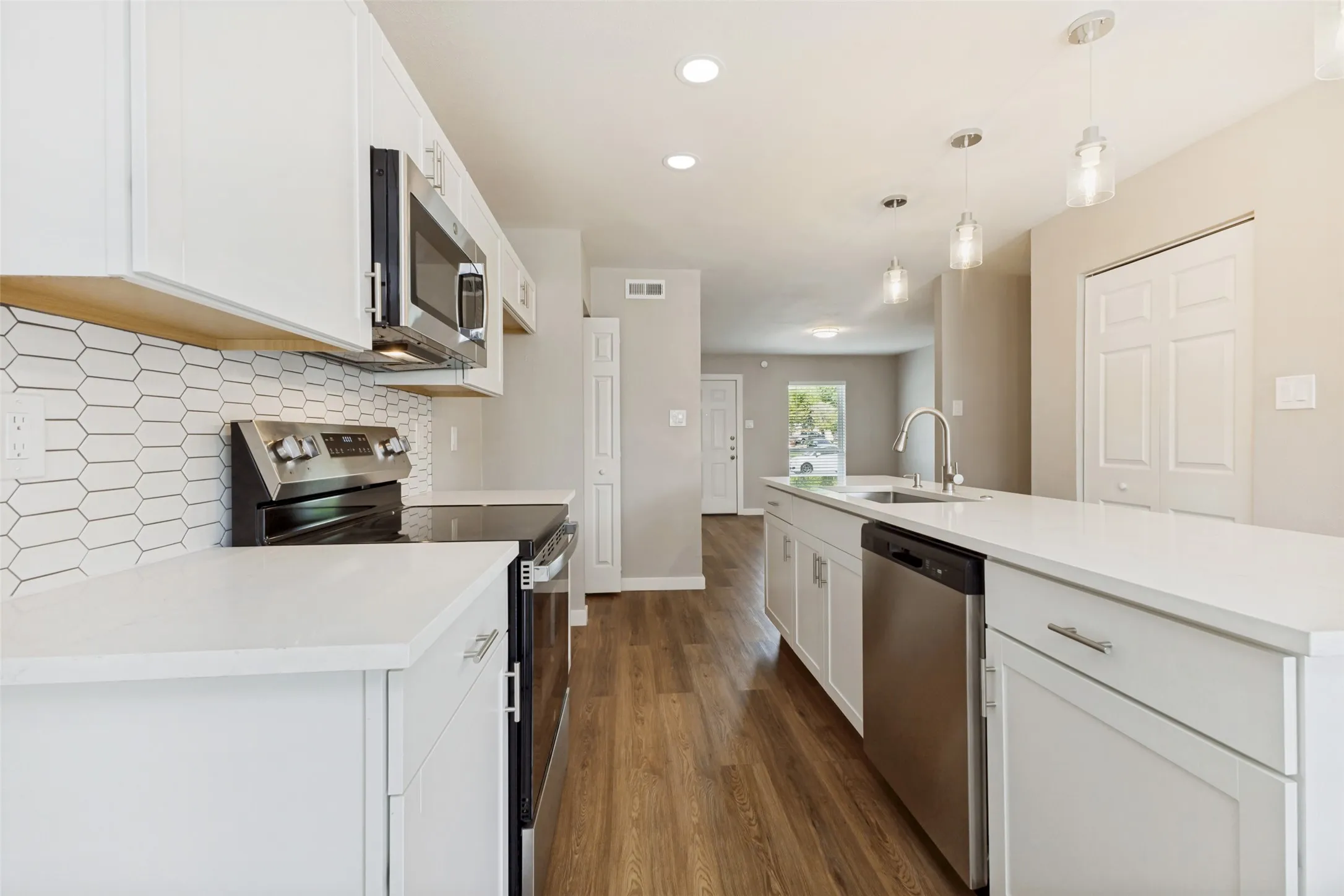 The kitchen is tastefully appointed, featuring a stylish backsplash over the electric stove plus microwave is conveniently mounted above.