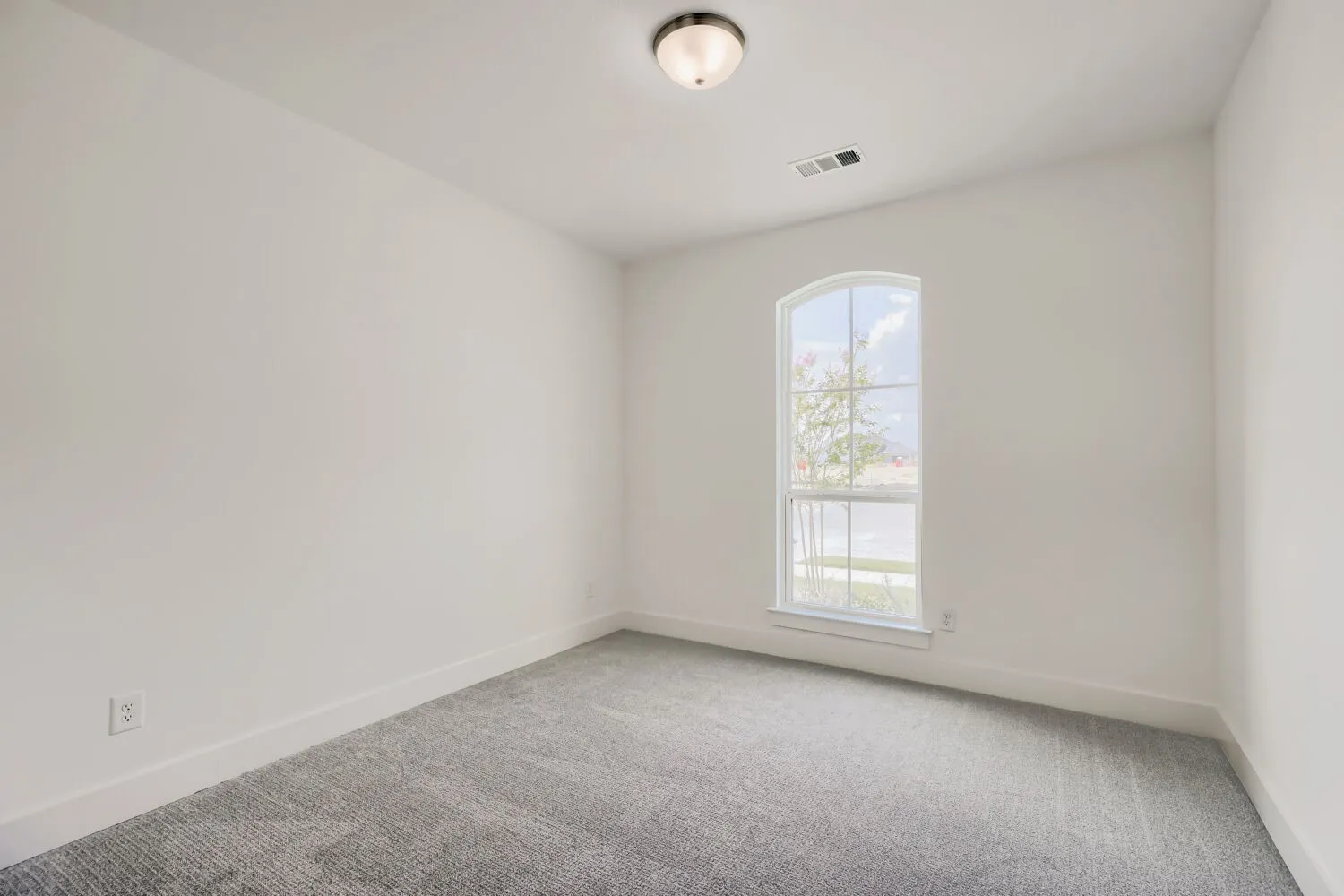 Interior space featuring an arched window, light gray carpet, white walls, and a semi-flush mount ceiling light