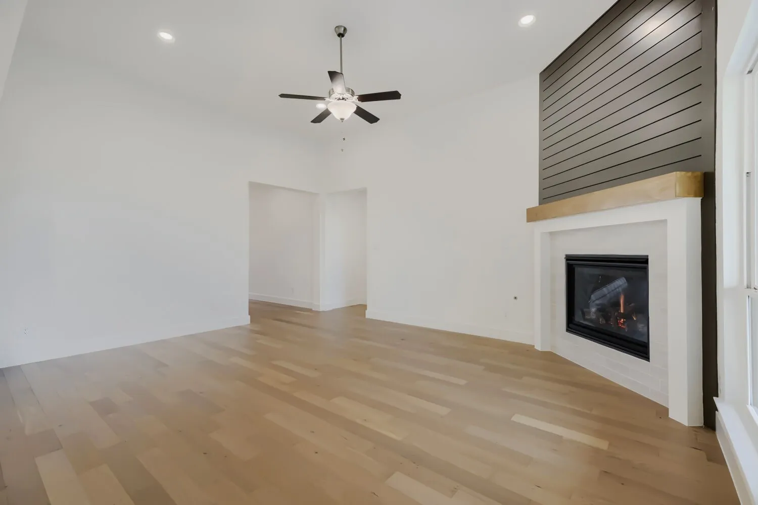Living space featuring a corner fireplace with a shiplap accent wall, a light wood-finish mantel, and a white surround
