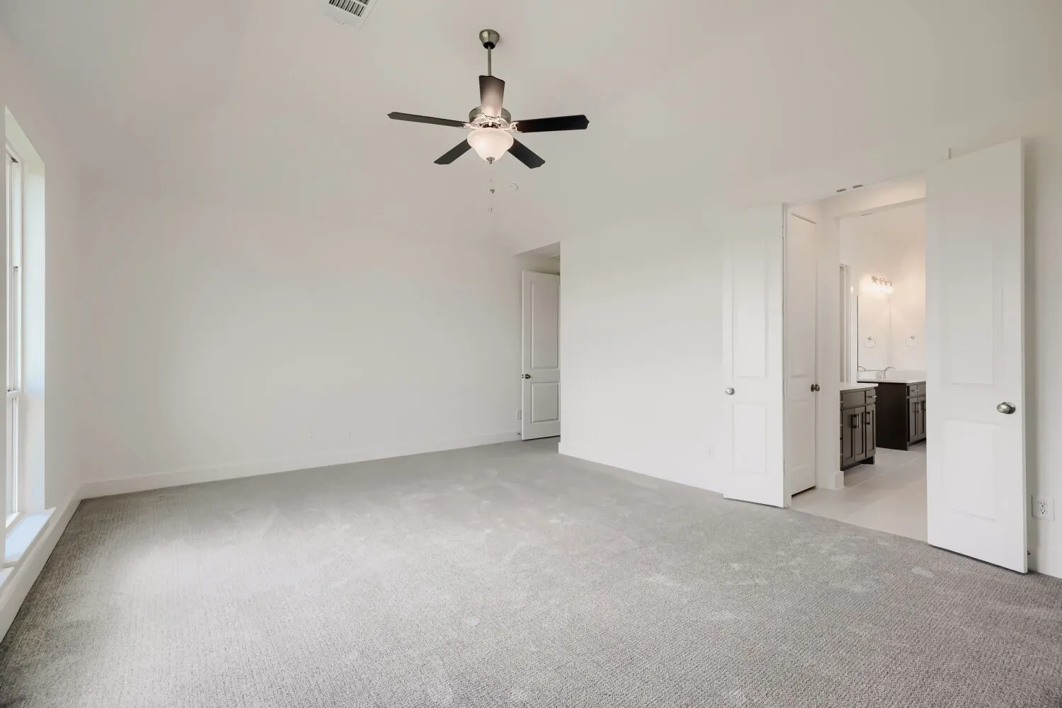 Spacious room featuring light gray carpeting, neutral wall finishes, and a ceiling fan with integrated lighting