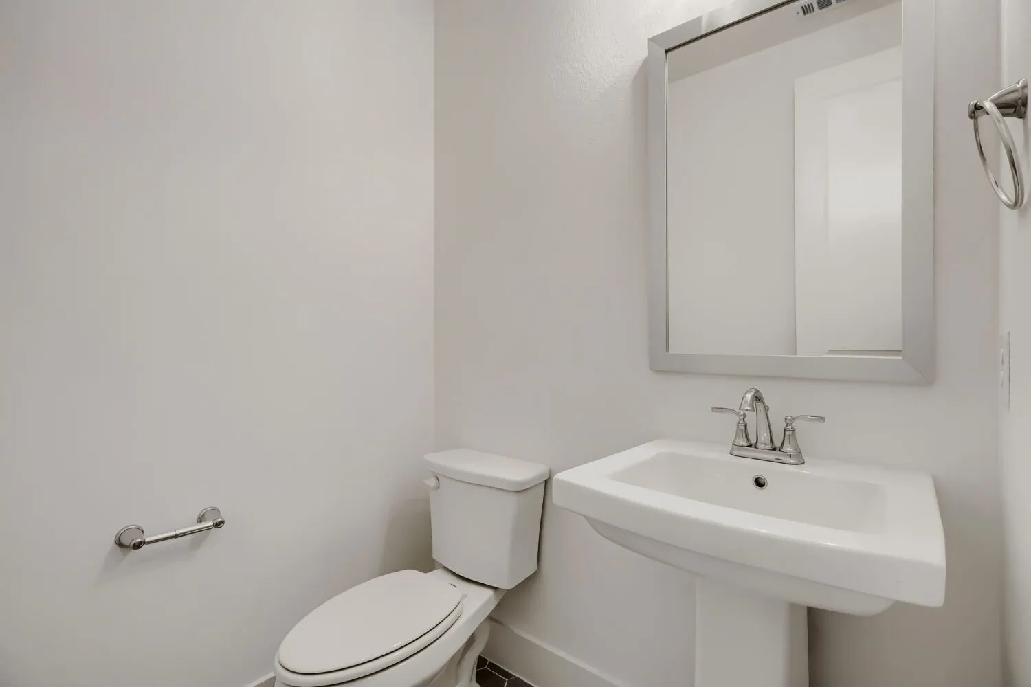 Pedestal sink with chrome faucet, framed mirror, and white toilet