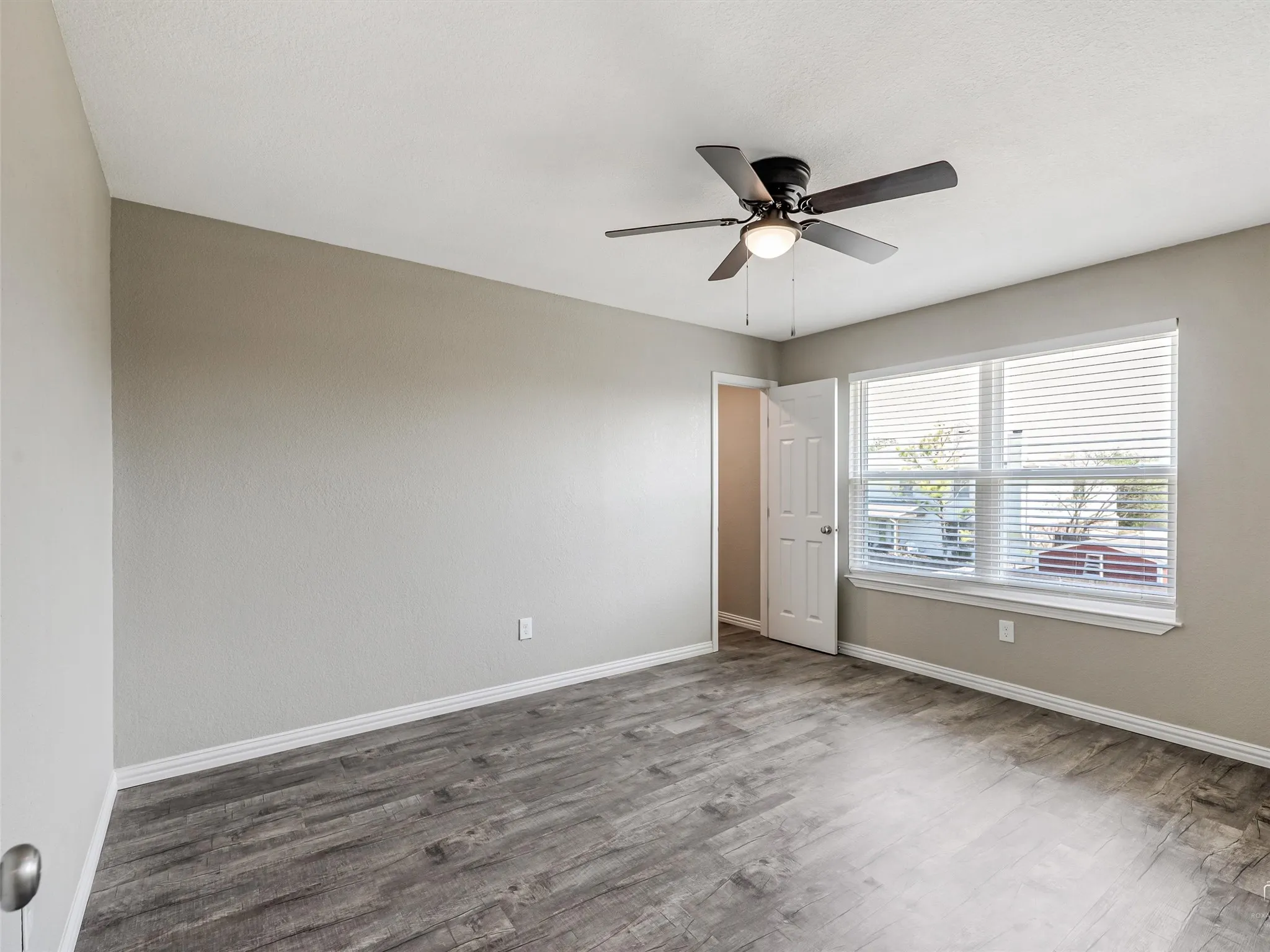 Bedroom featuring light gray wall paint, wood-finish flooring, and a ceiling fan with integrated lighting