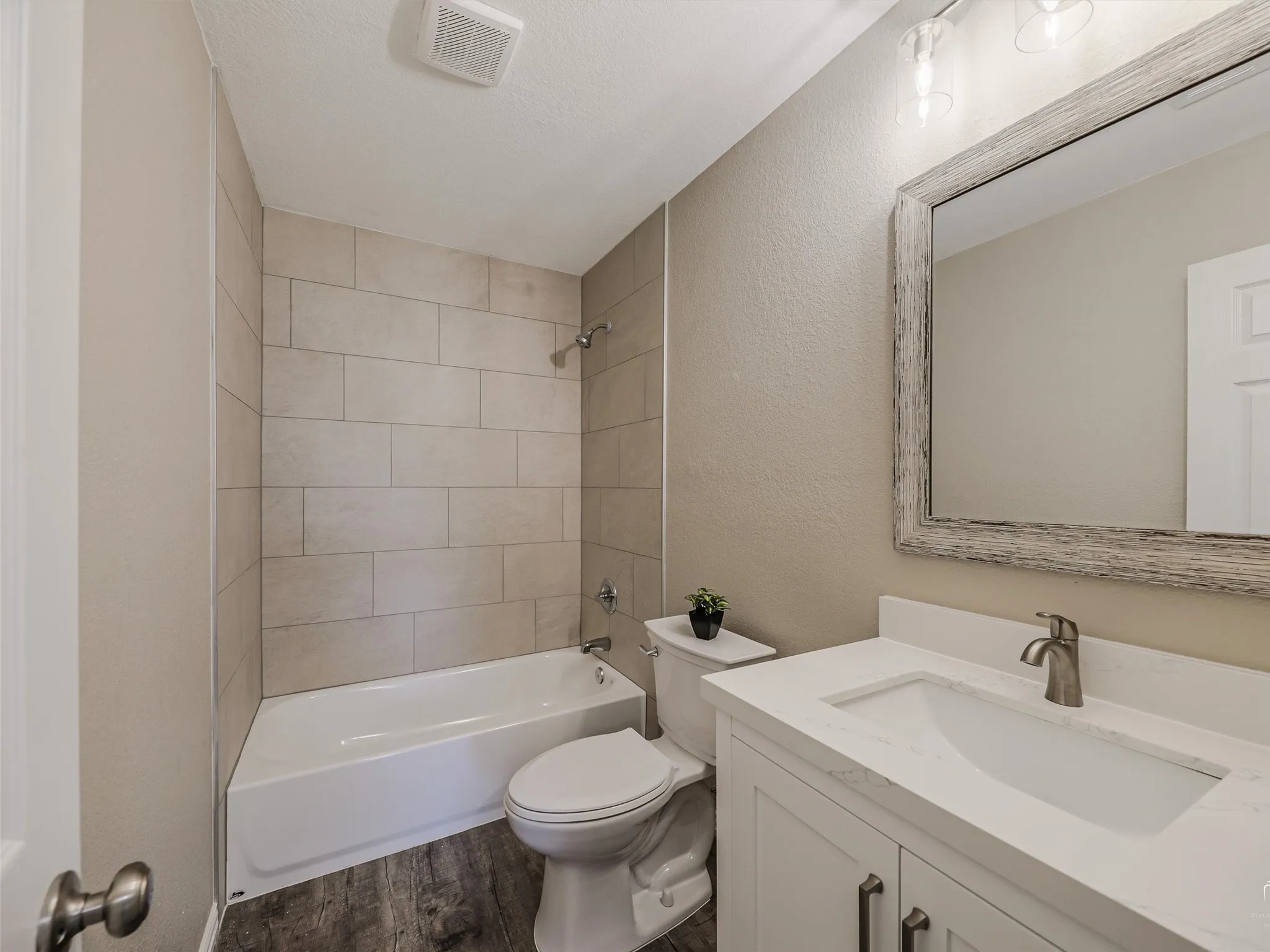 White vanity with a single basin sink, brushed nickel faucet, and a large distressed wood-framed mirror
