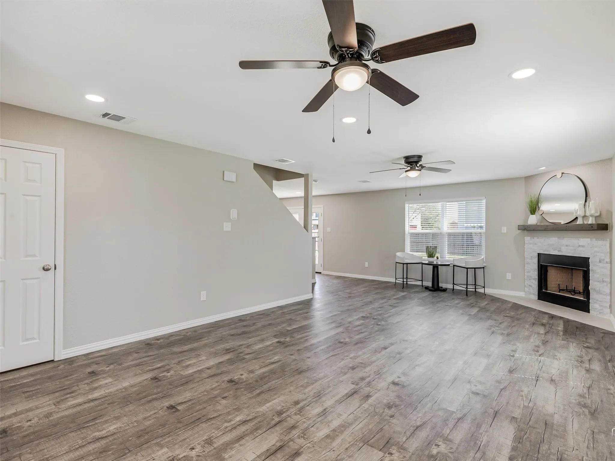 Spacious living area featuring wood-finish flooring, recessed lighting, and ceiling fans