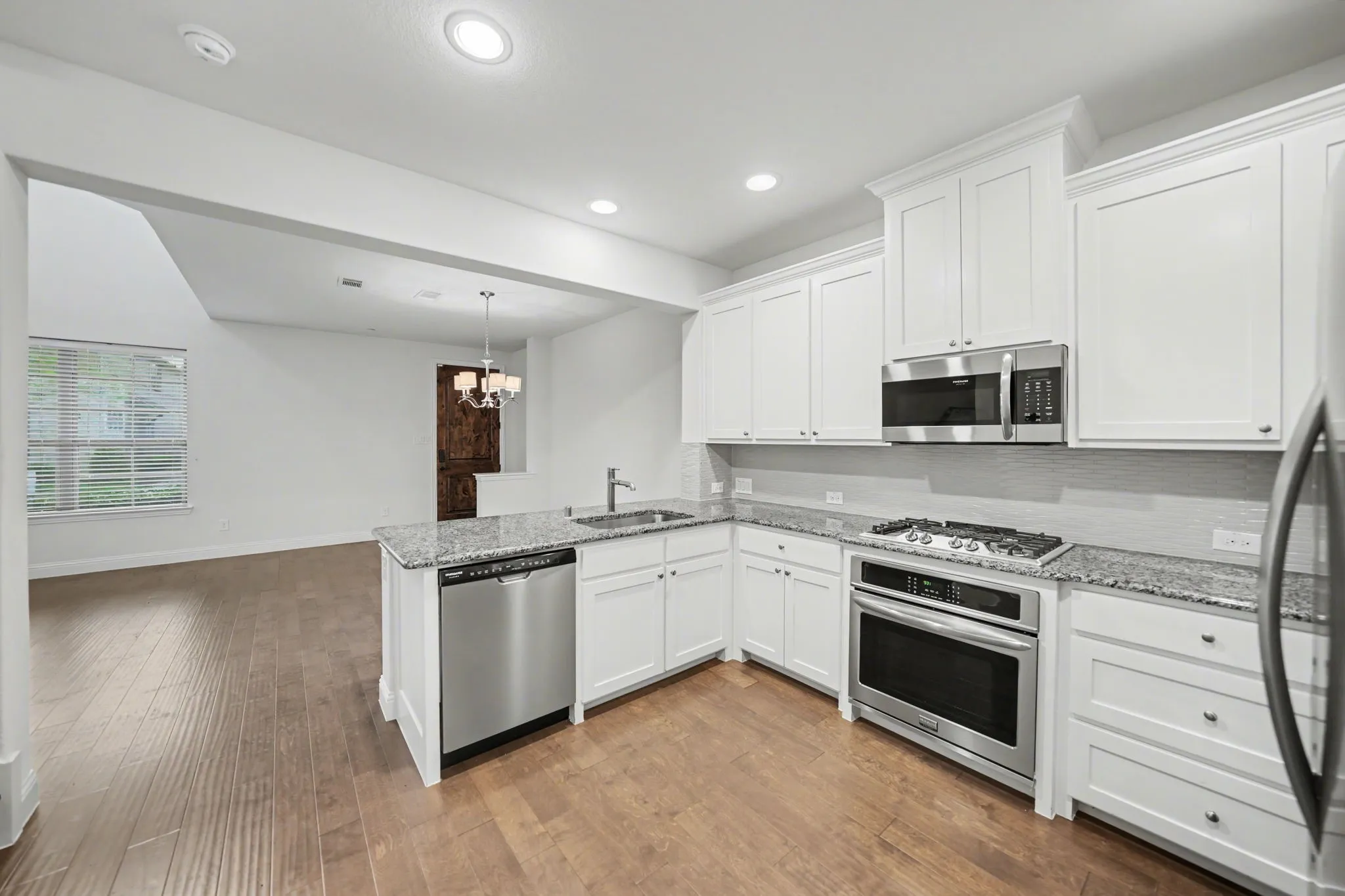 Kitchen featuring white cabinets, light stone counters, stainless steel appliances, and a chandelier
