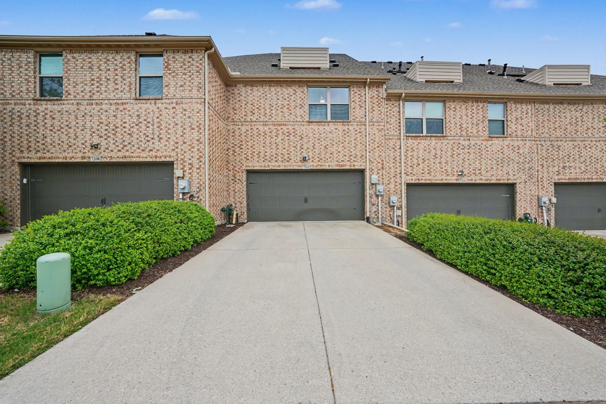 View of front of property with an attached garage, driveway, and brick siding
