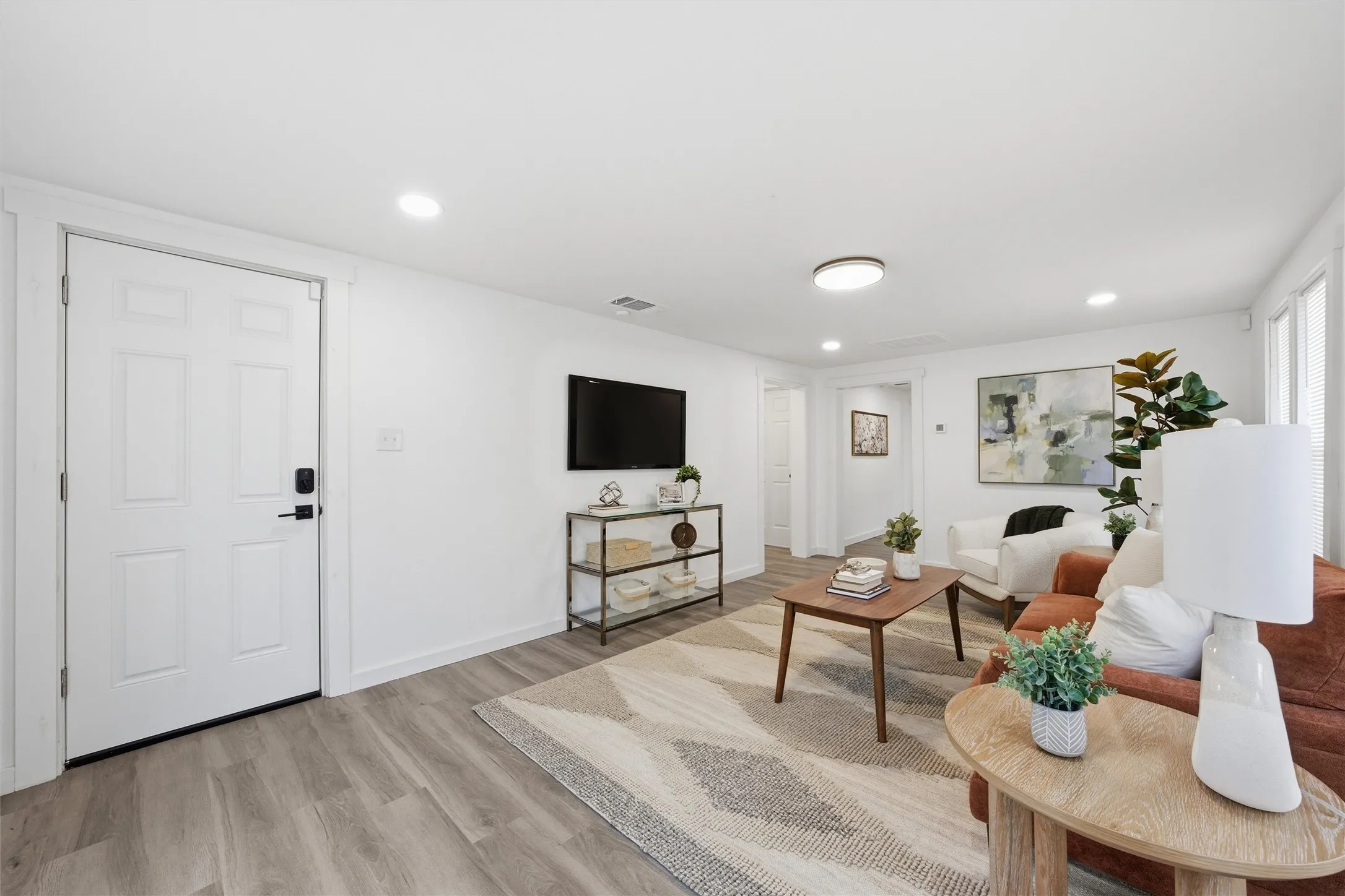 Living area with light wood finished floors and recessed lighting