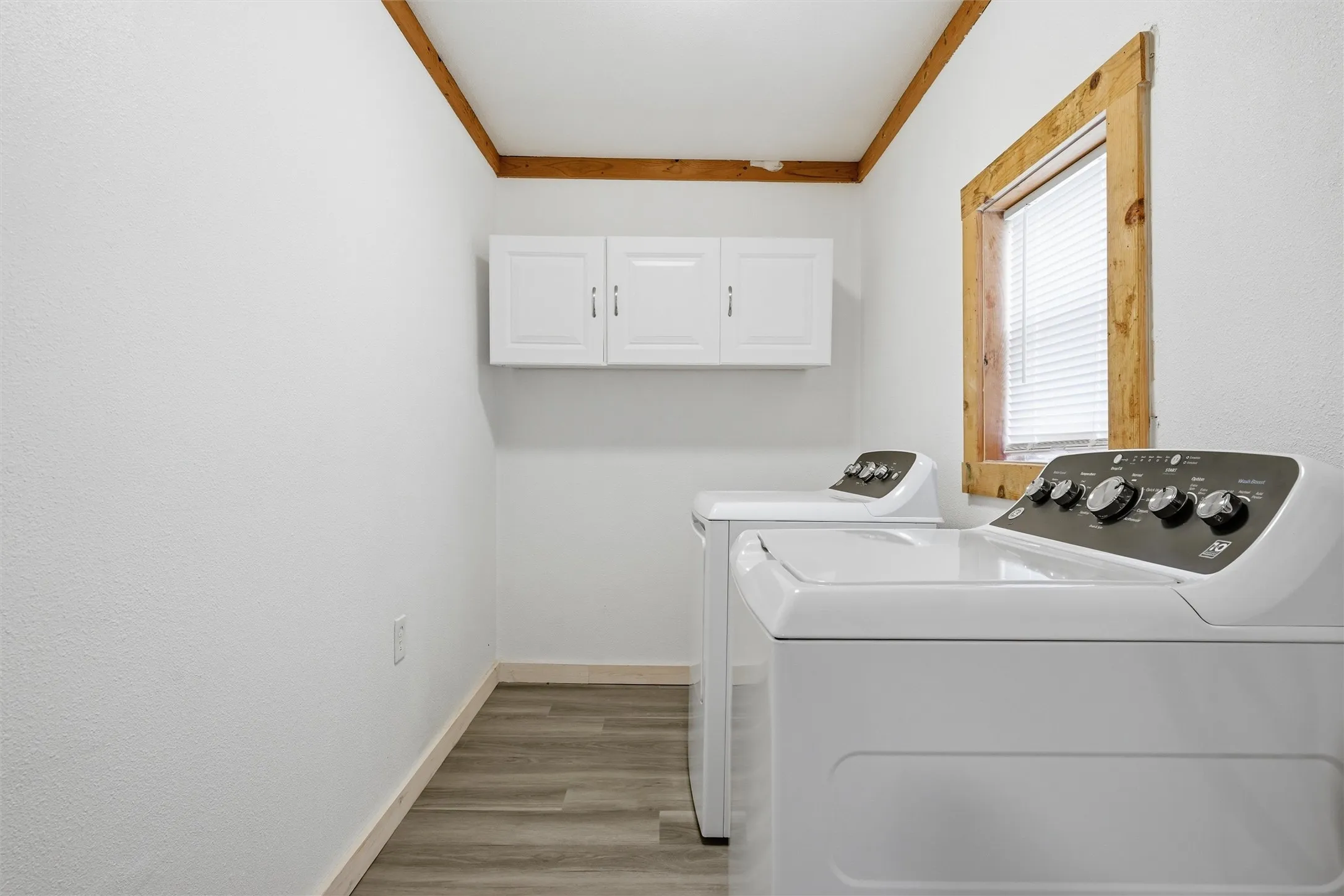 Laundry area featuring independent washer and dryer, light wood-type flooring, cabinet space, and crown molding